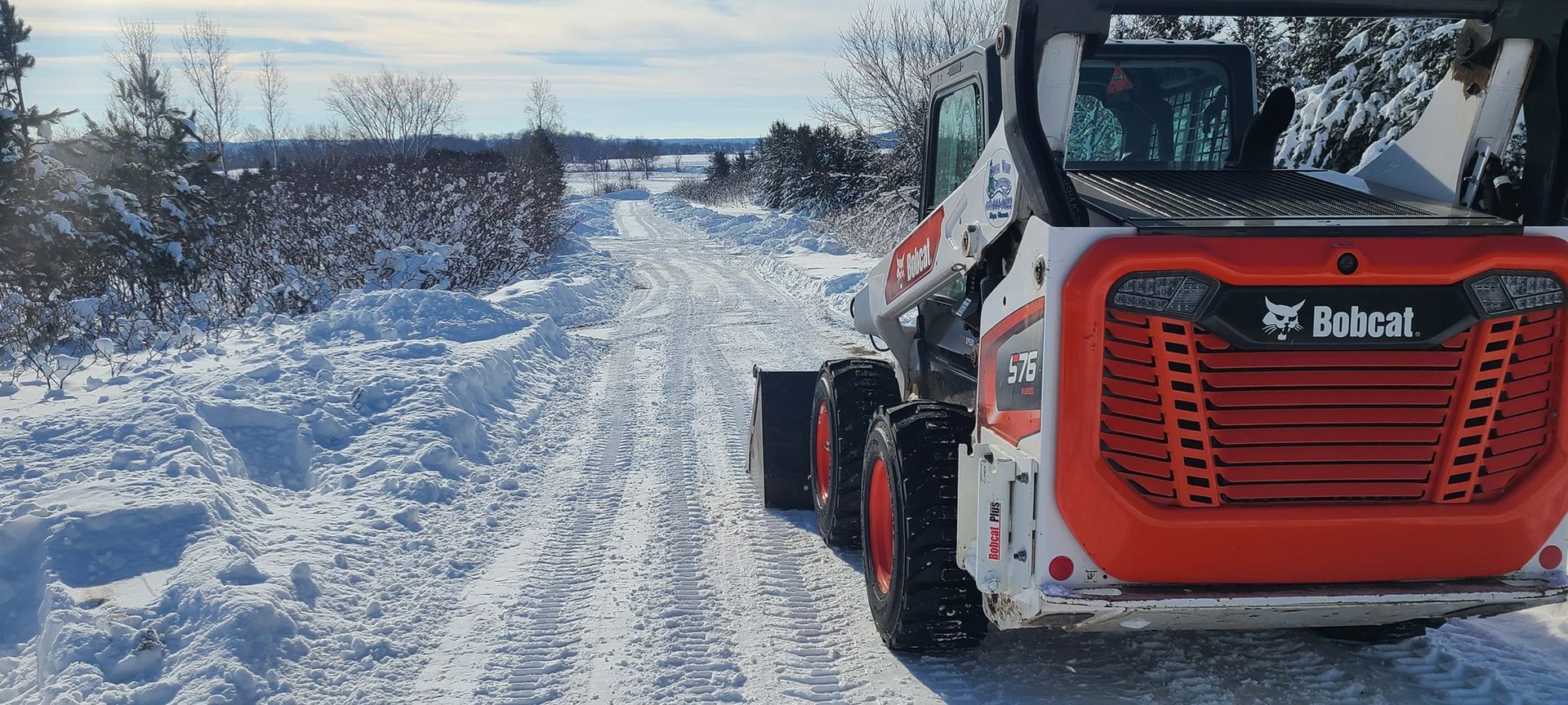 A bobcat is driving down a snowy road.
