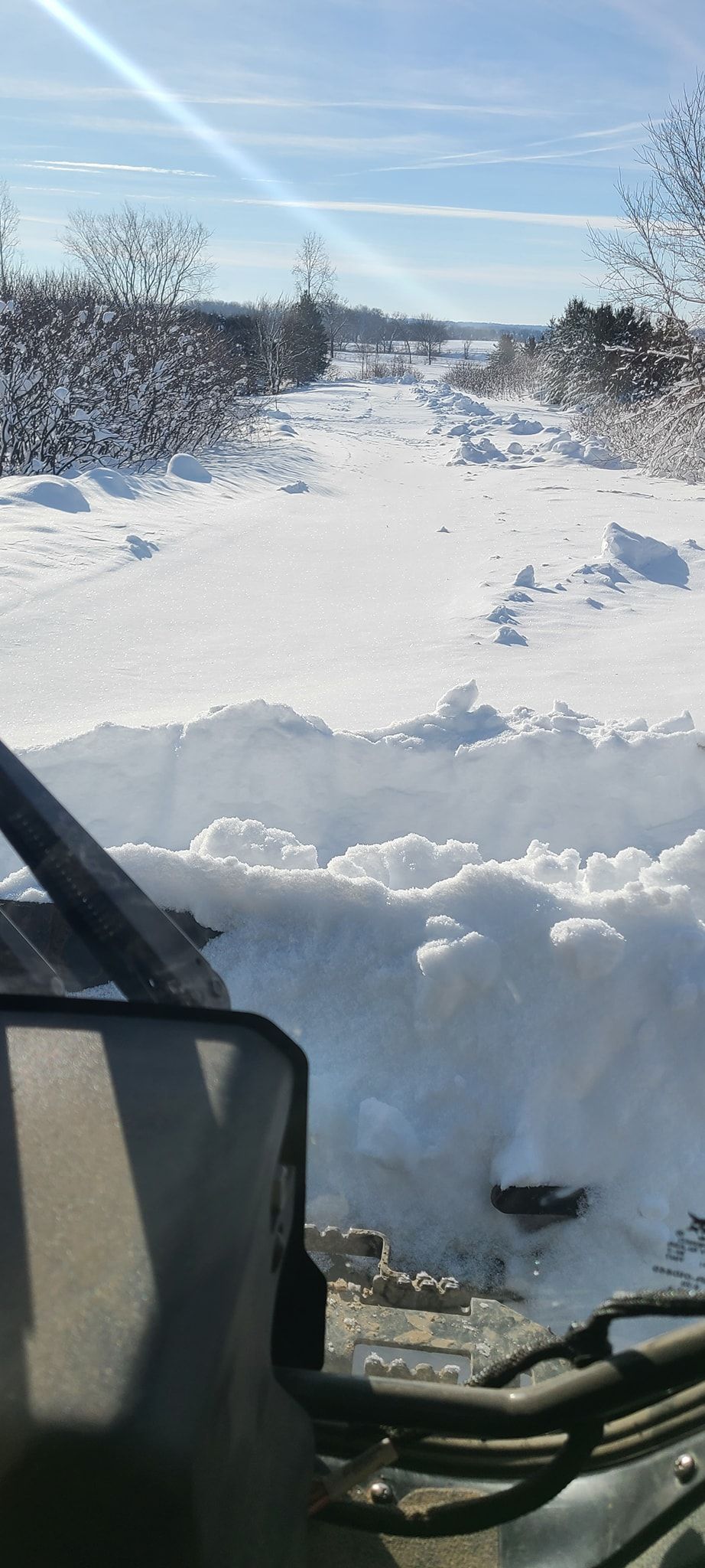 A snowy field is visible through the windshield of a vehicle.
