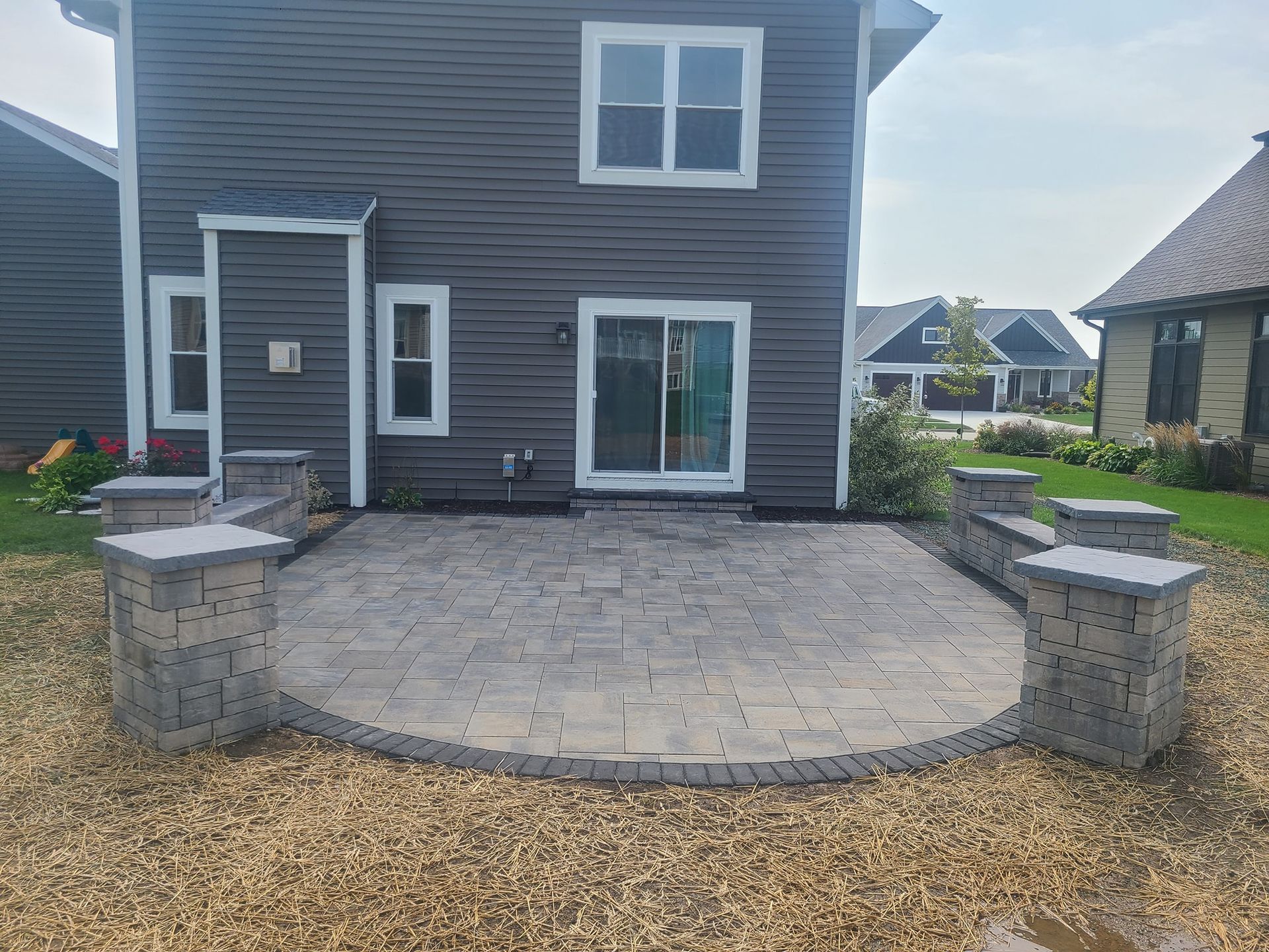 A large gray house with a patio in front of it.