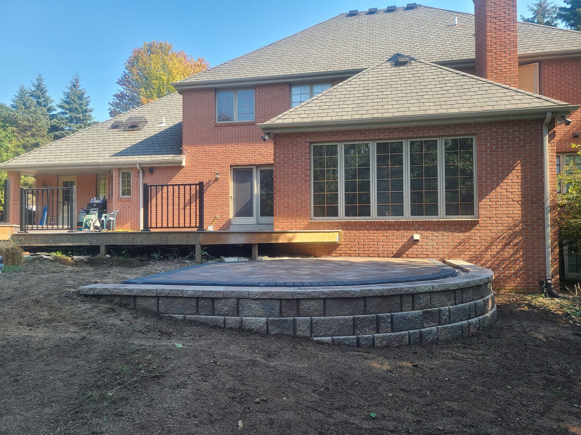 A large brick house with a large deck and a hot tub in front of it.