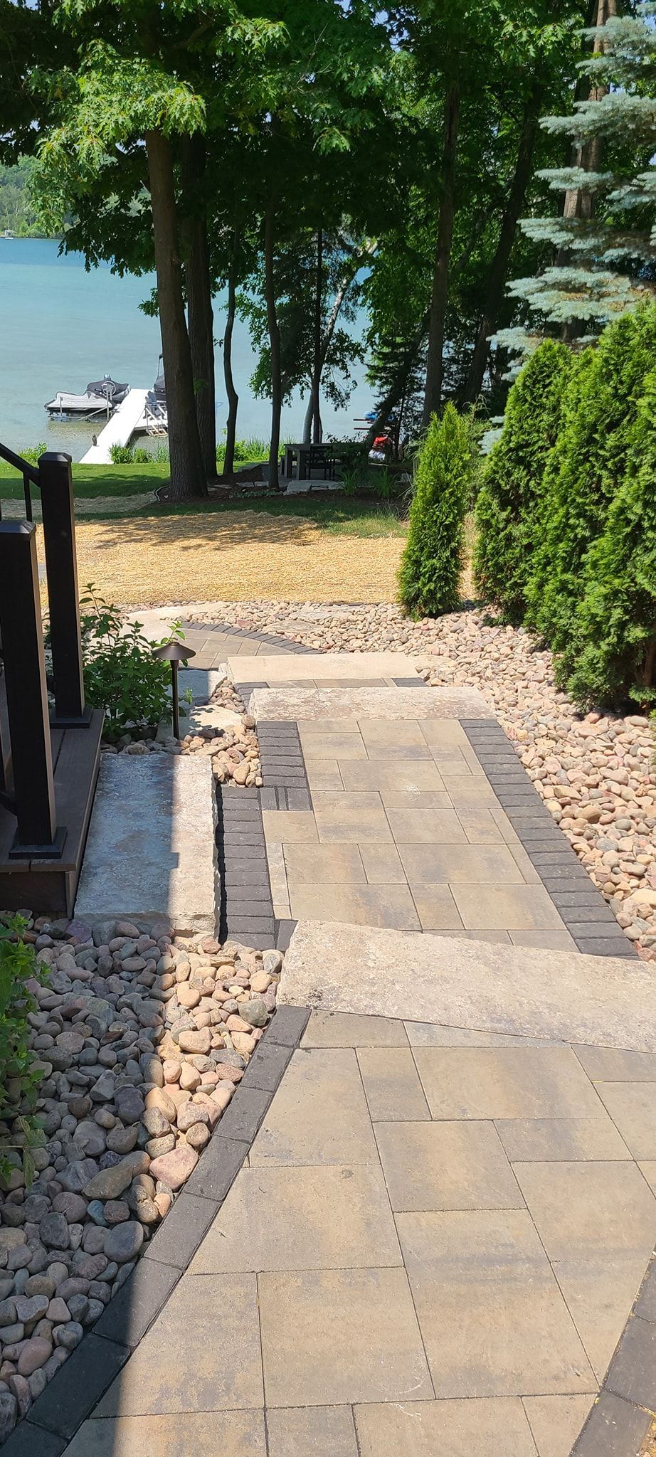 A stone walkway leading to a lake surrounded by trees and rocks.