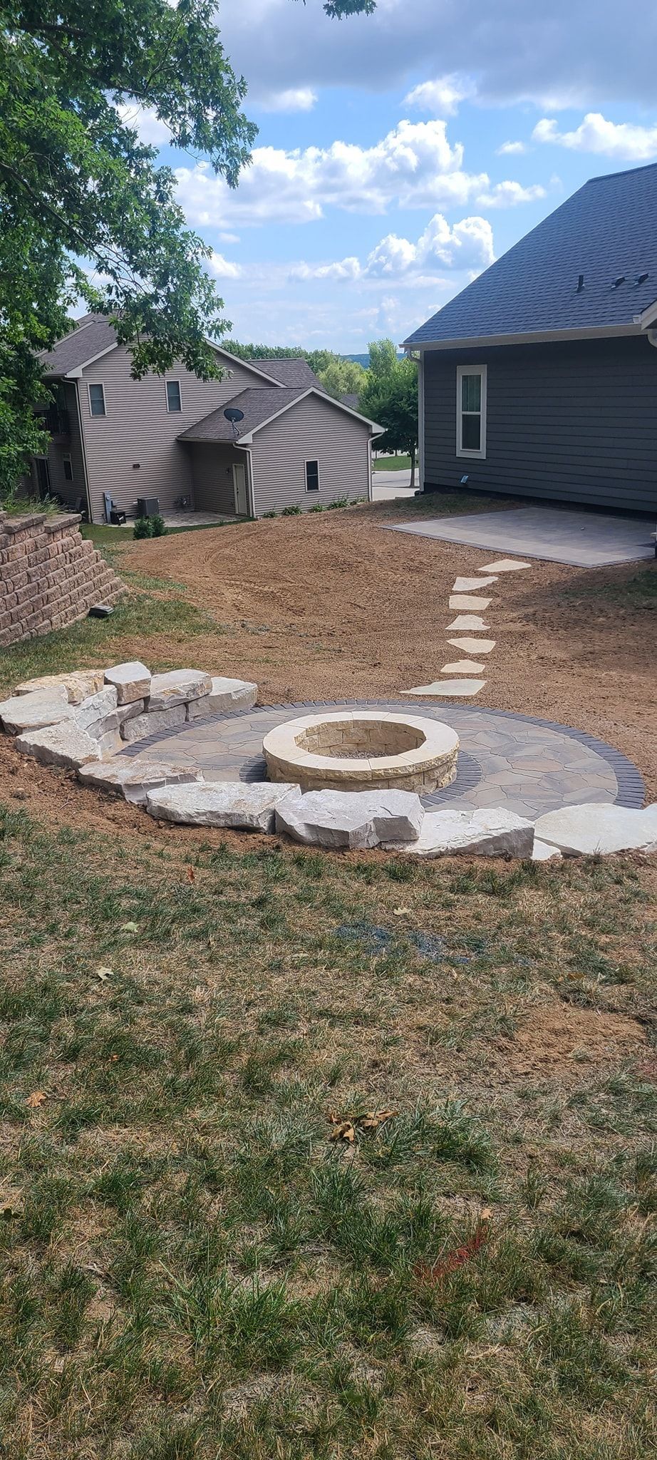 A fire pit is sitting in the middle of a lush green yard next to a house.