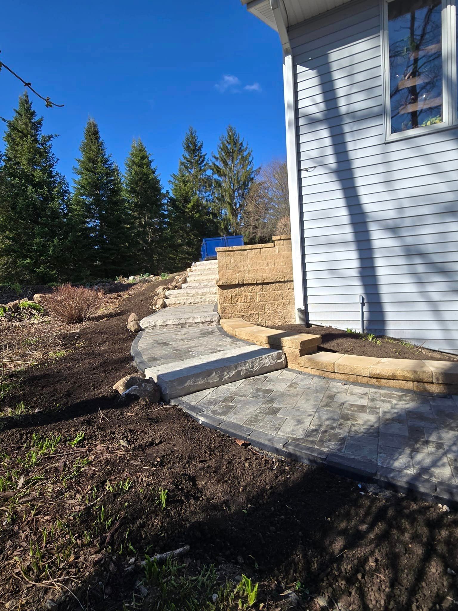 A house with a walkway leading to it and trees in the background.