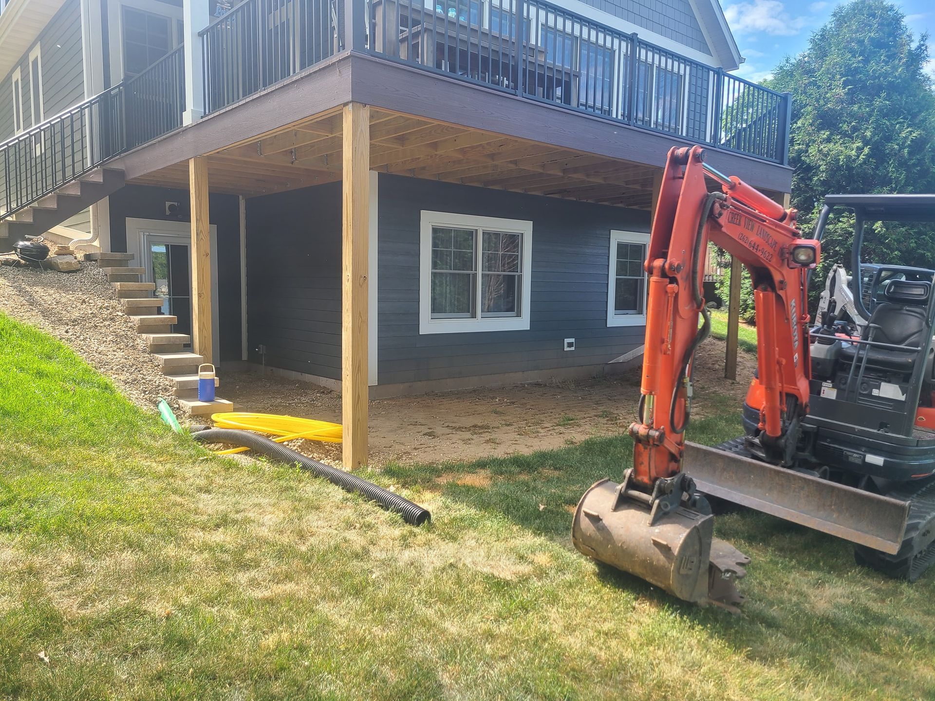 An excavator is parked in front of a house under construction.