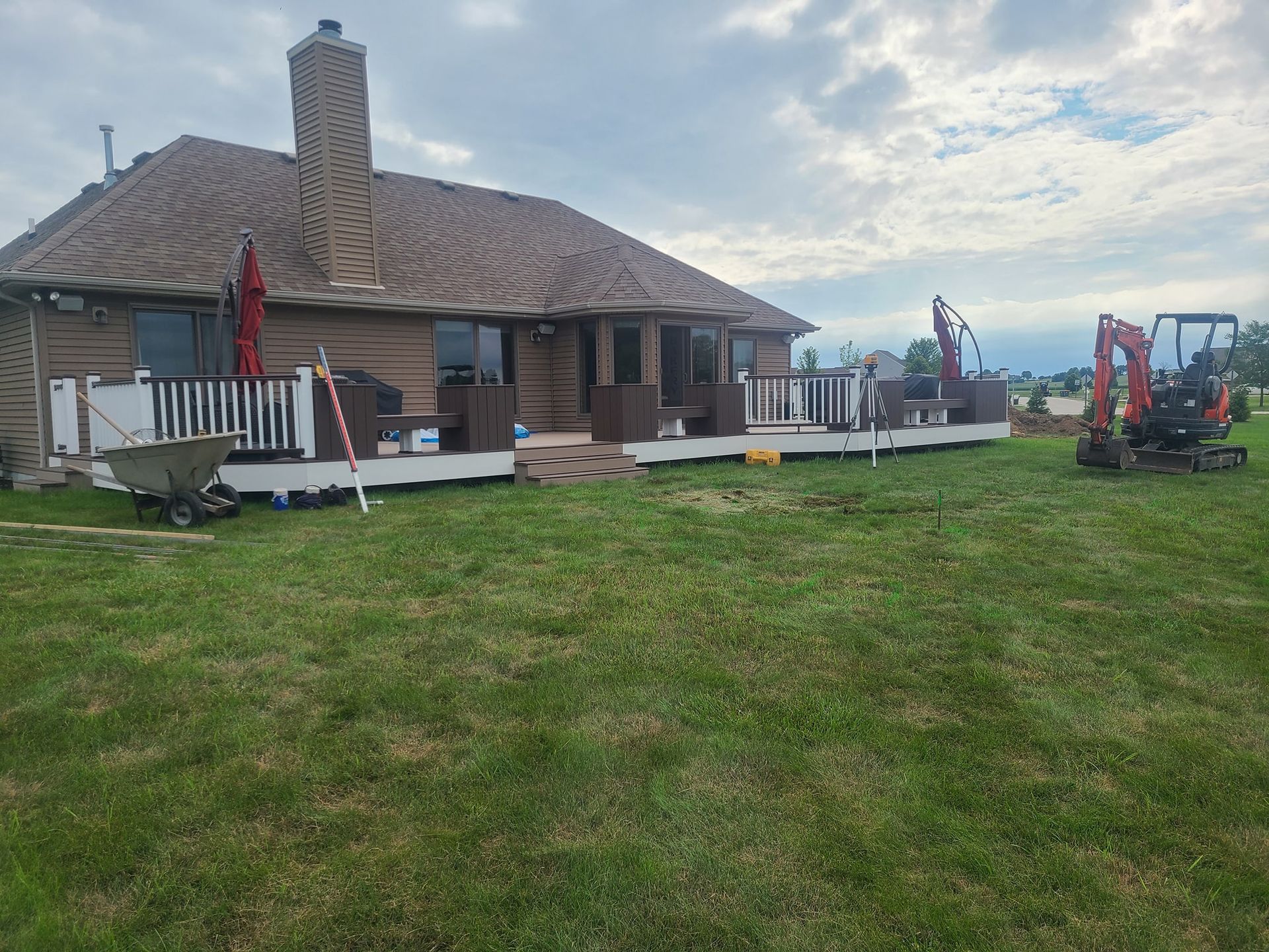 A house with a deck and a tractor in front of it.