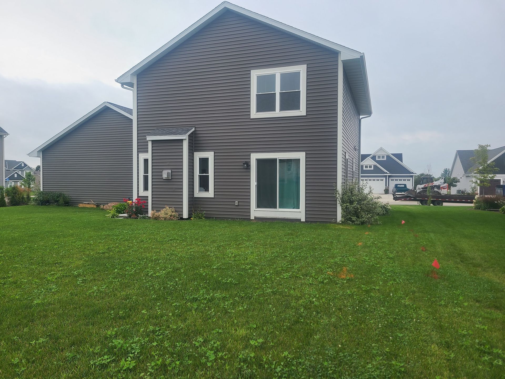A house with a lot of windows is sitting on top of a lush green field.