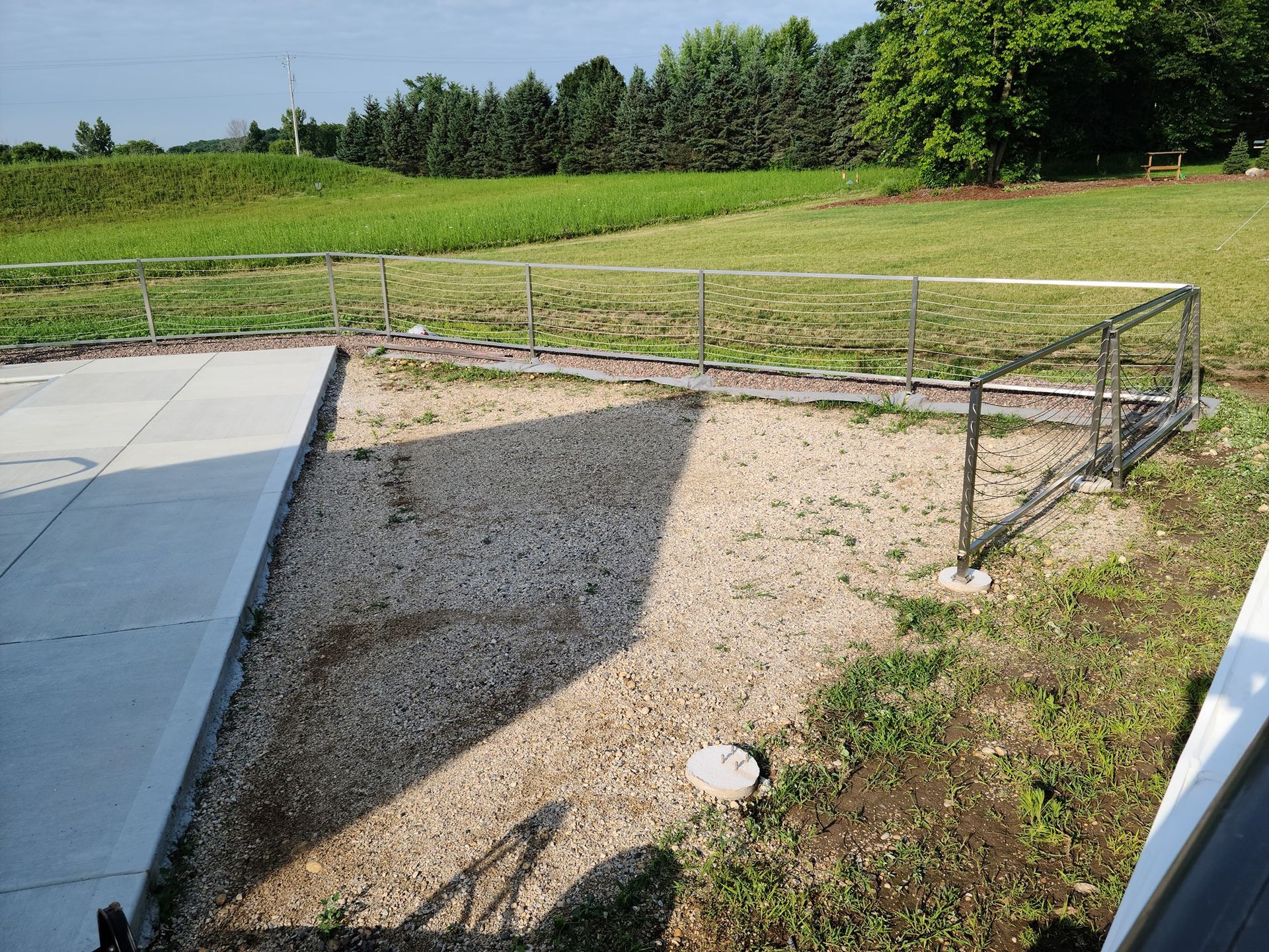 A gravel path leading to a grassy field with trees in the background