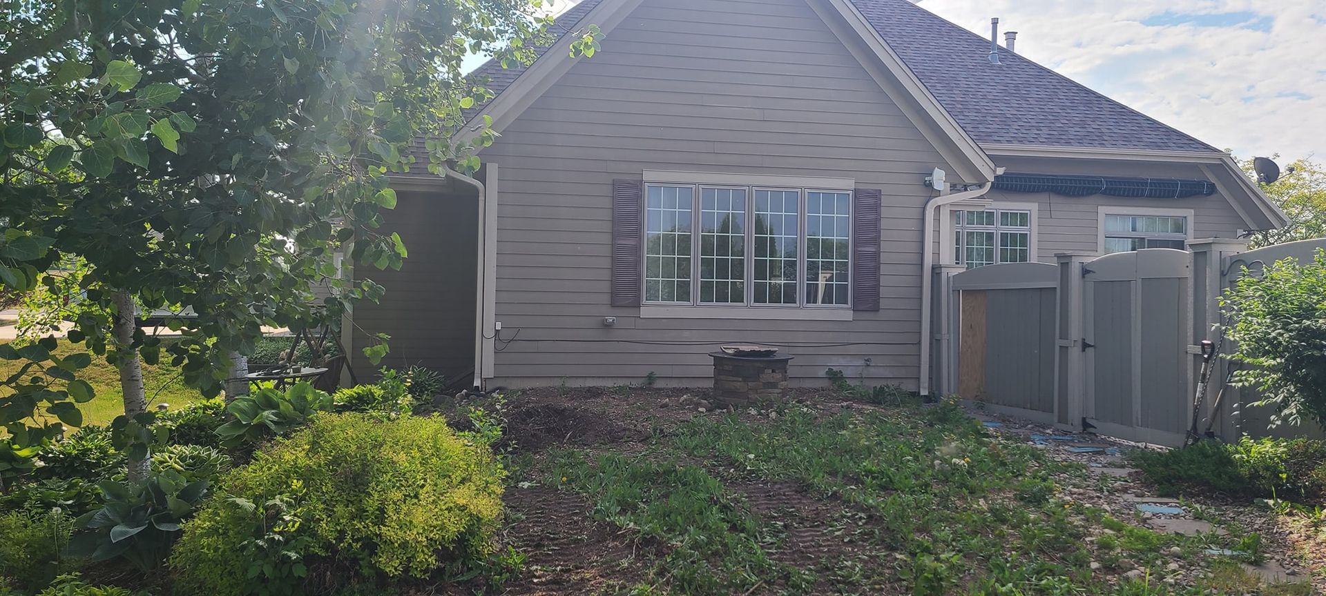 A small house with a lot of windows is surrounded by trees and bushes.