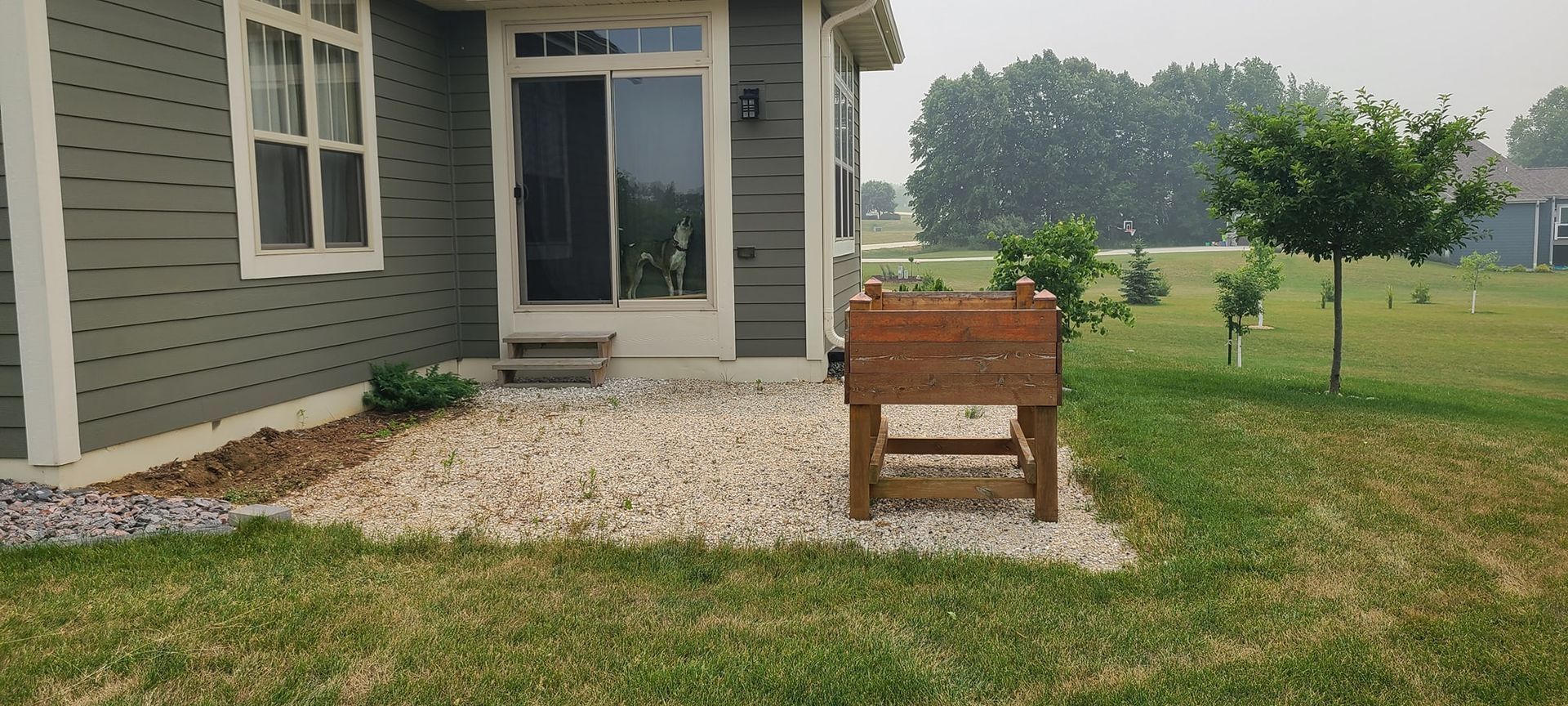 A house with a patio and a wooden planter in front of it.