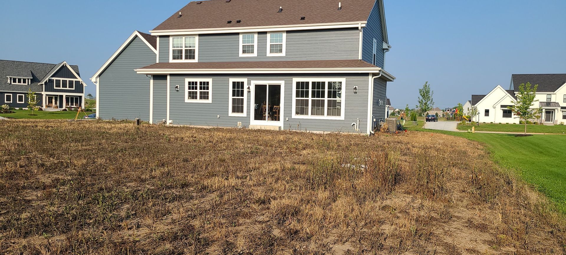A large house is sitting in the middle of a lush green field.