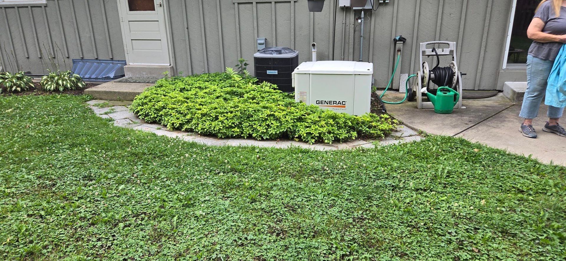 A woman is standing in the grass in front of a house.
