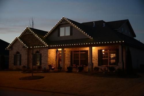 House exterior at dusk, decorated with white Christmas lights on the roof