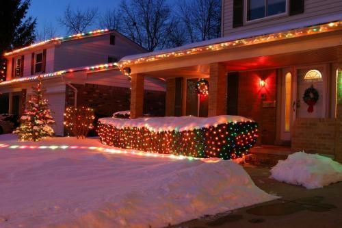 House with Christmas lights and snow-covered yard at dusk
