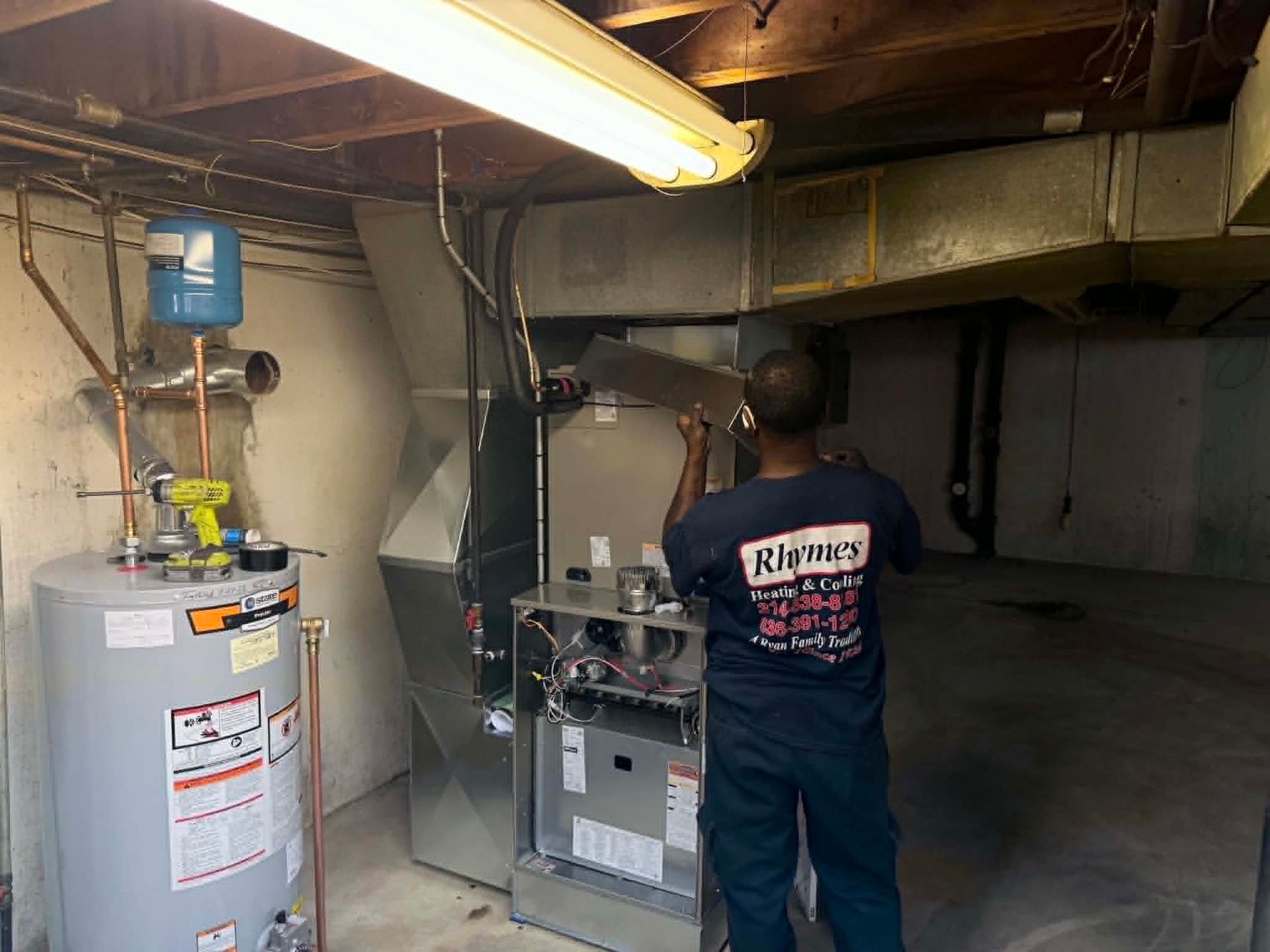 Technician inspecting a water heater and furnace in a basement utility room