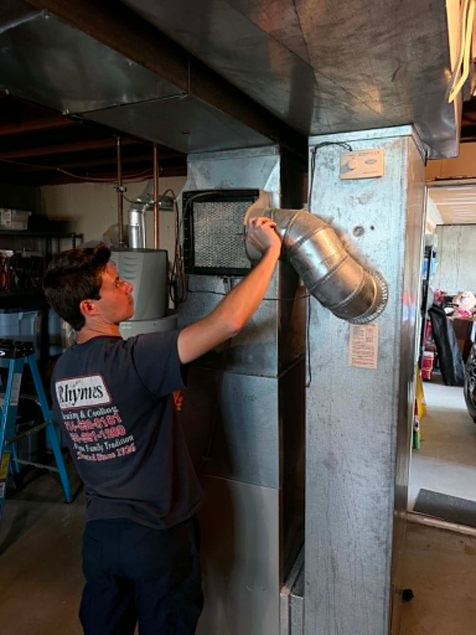 Worker inspecting a metal duct inside an industrial workshop