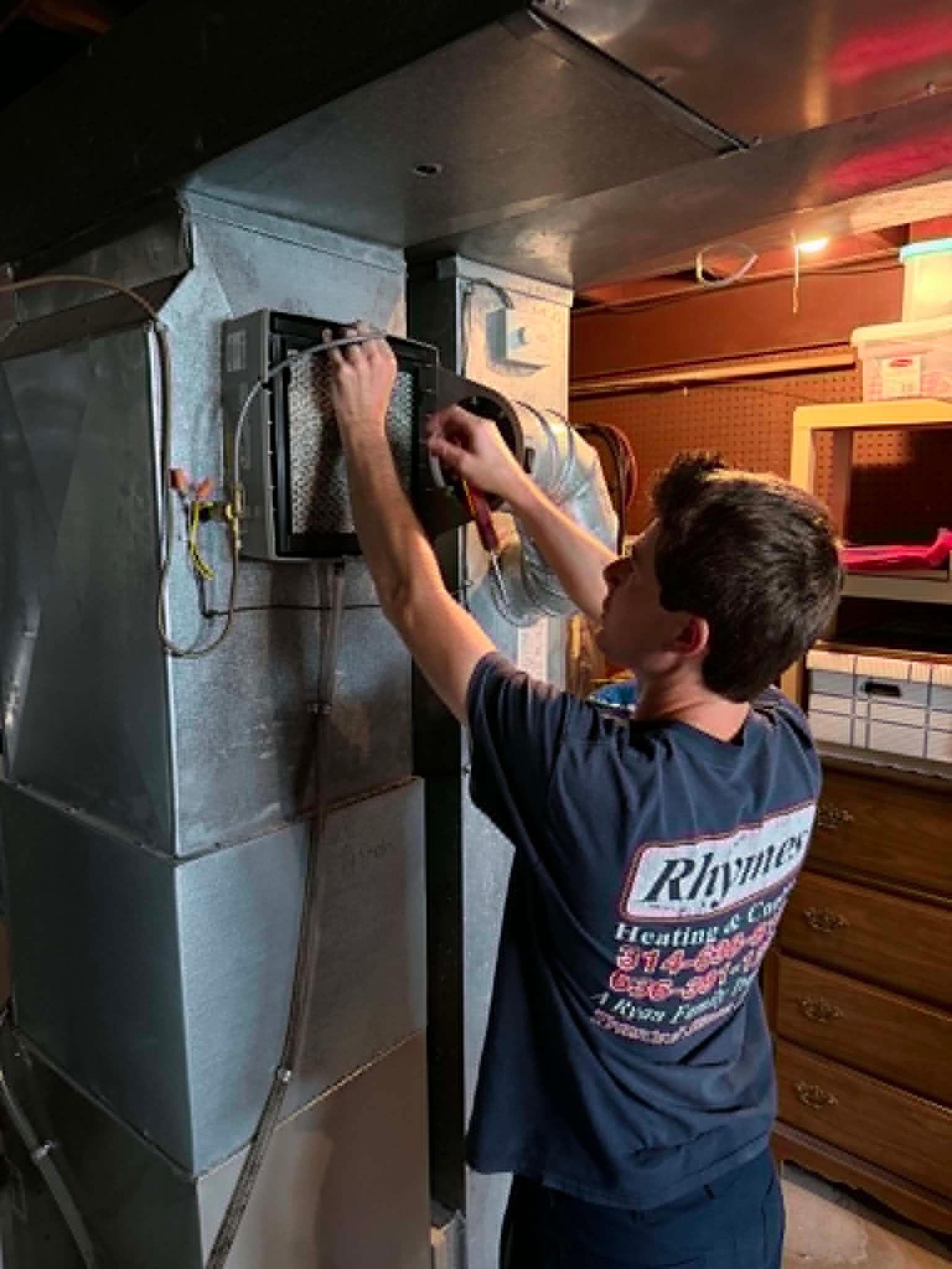 Person using a wrench to work on metal ducting in a utility room