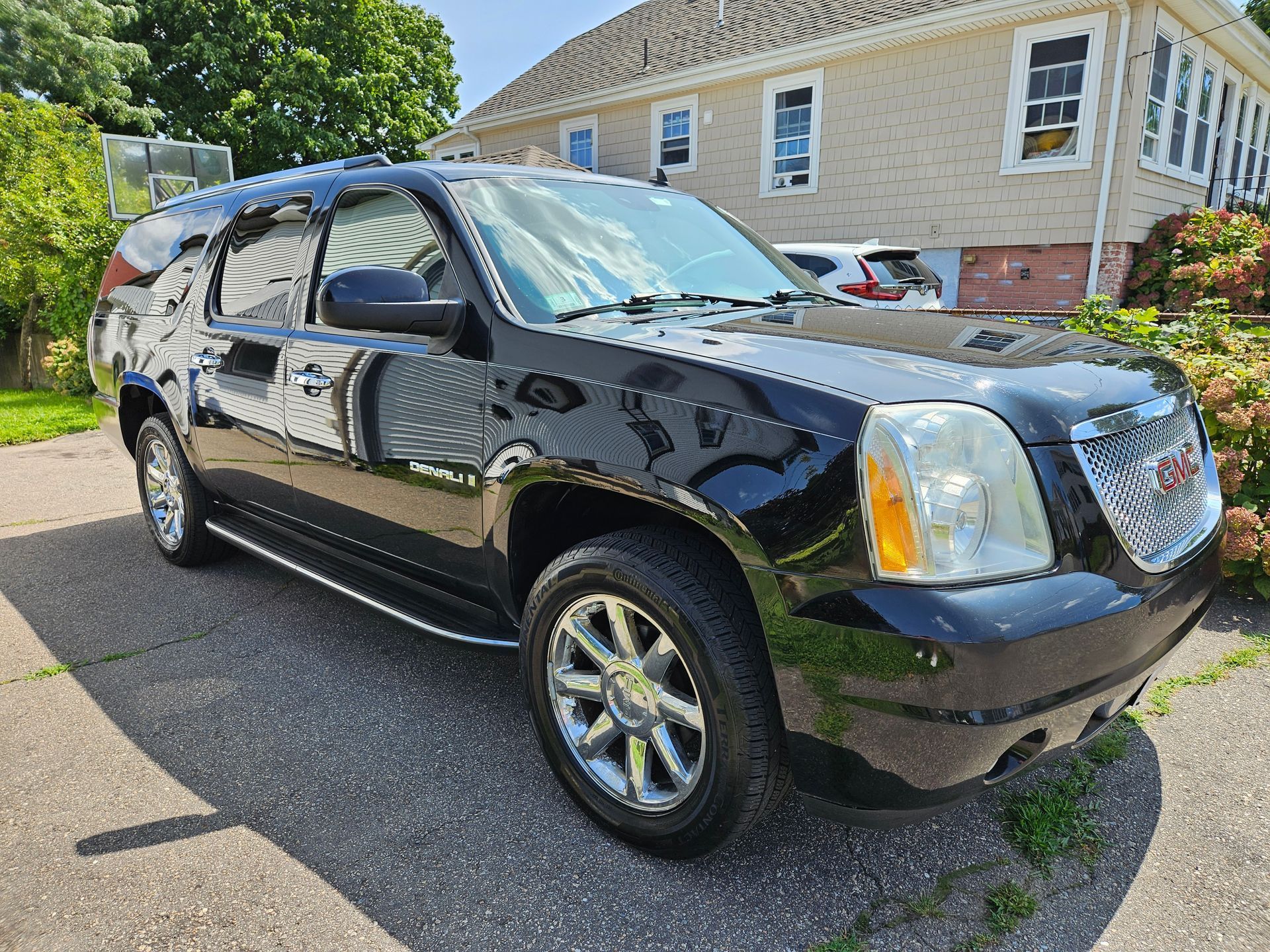 A black suv is parked in front of a house.