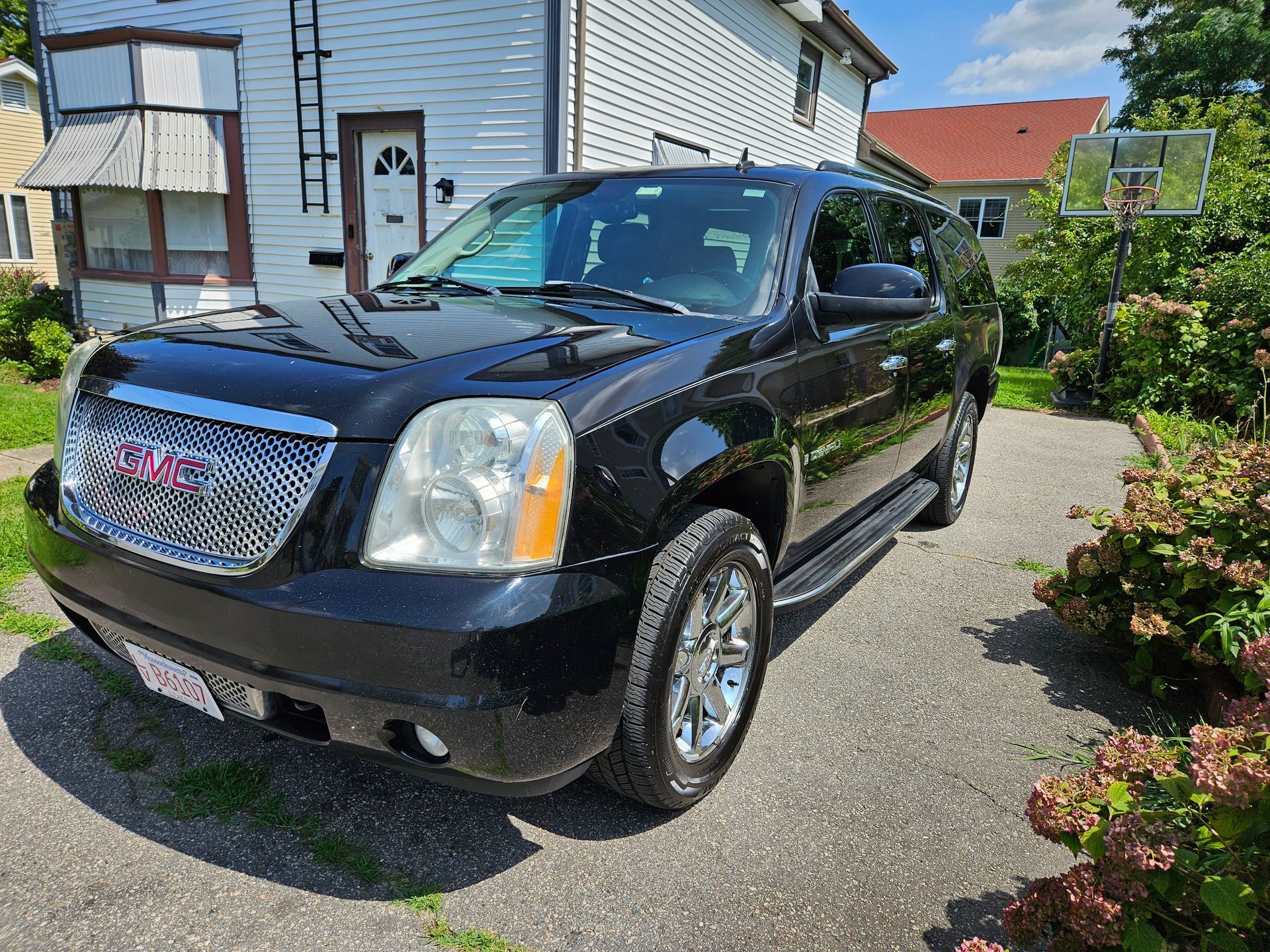 A black gmc yukon is parked in a driveway in front of a house.