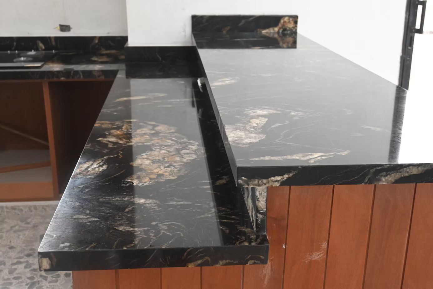 Black granite countertop with gold veining over wooden cabinetry.