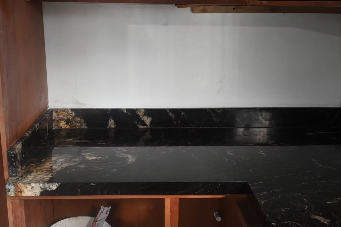 Black granite countertop with white wall backsplash in a kitchen setting.