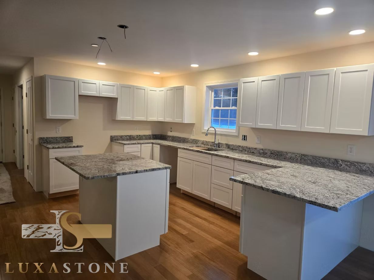 Modern kitchen with white cabinets, granite countertops, and wood floors.