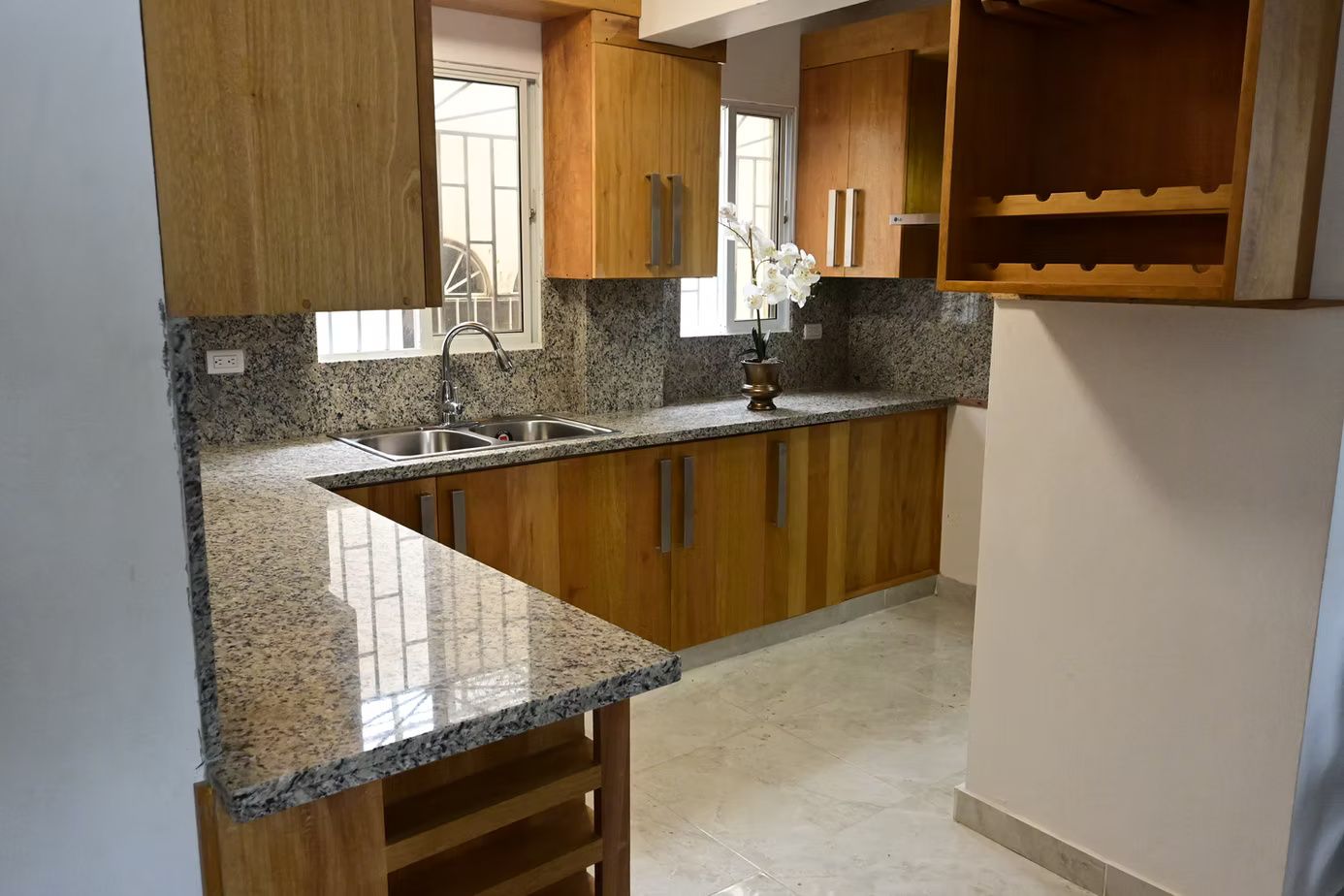 L-shaped kitchen with wooden cabinets, granite countertops, and a stainless steel sink.