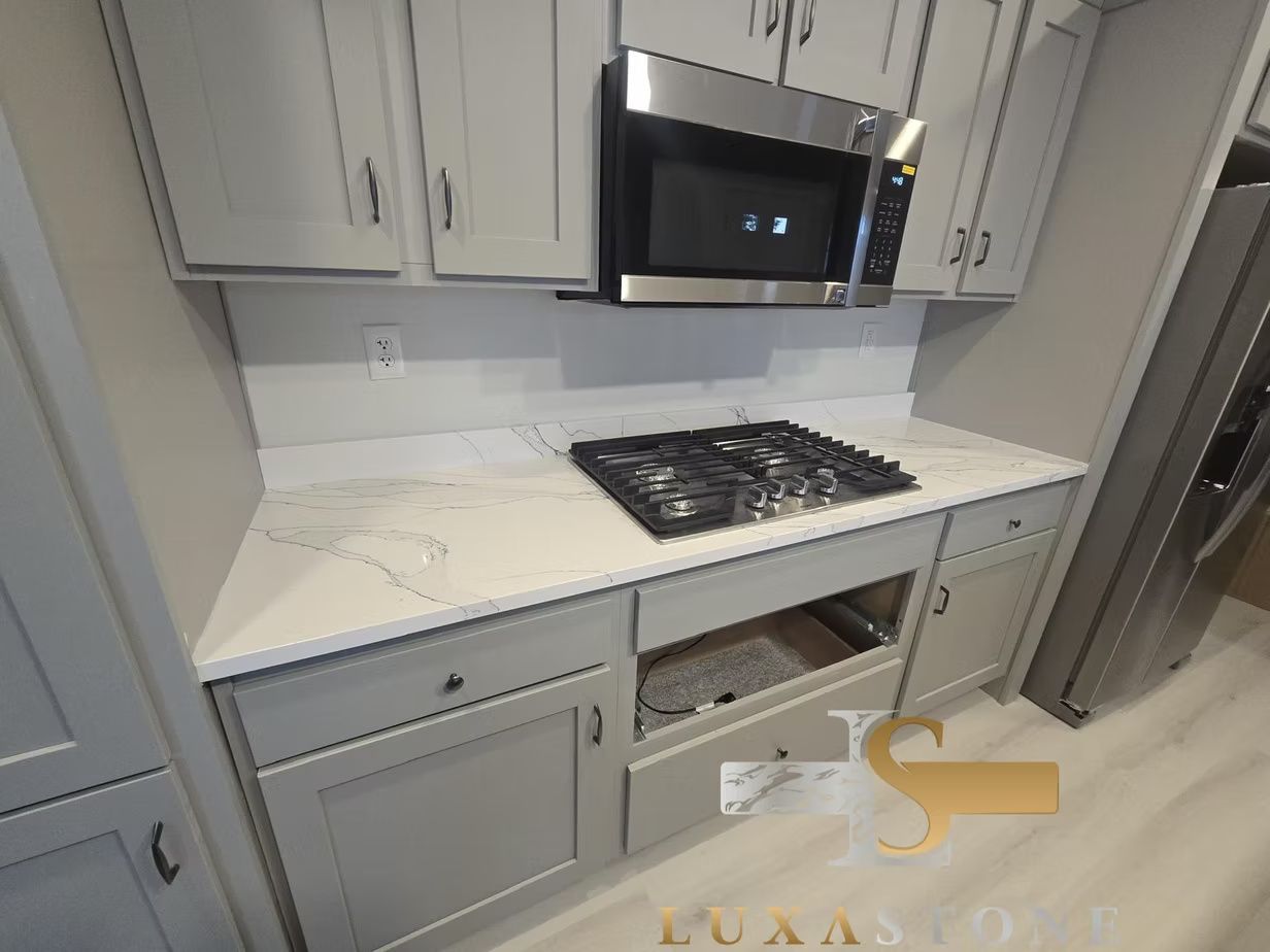 Kitchen with gray cabinets, white countertop, gas cooktop, and microwave.