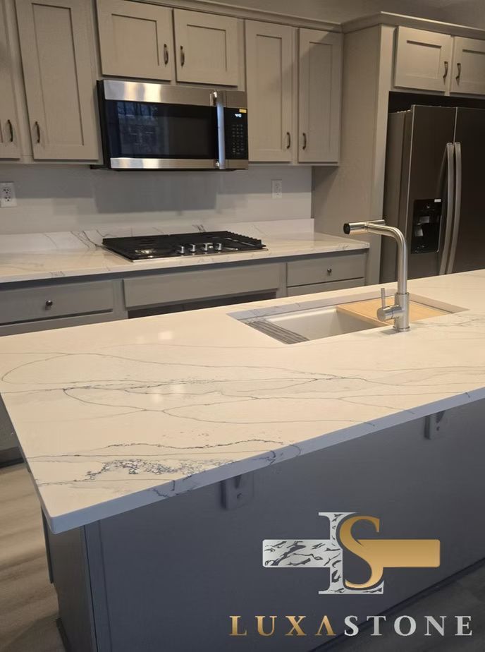 Kitchen with white marble countertops, gray cabinets, stainless steel appliances, and a central island.