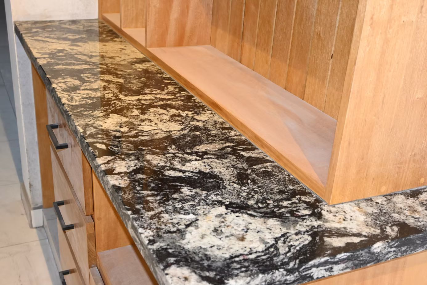 Granite countertop on wooden shelves, with black, white, and tan swirls.