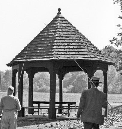 A black and white photo of two men in front of a gazebo