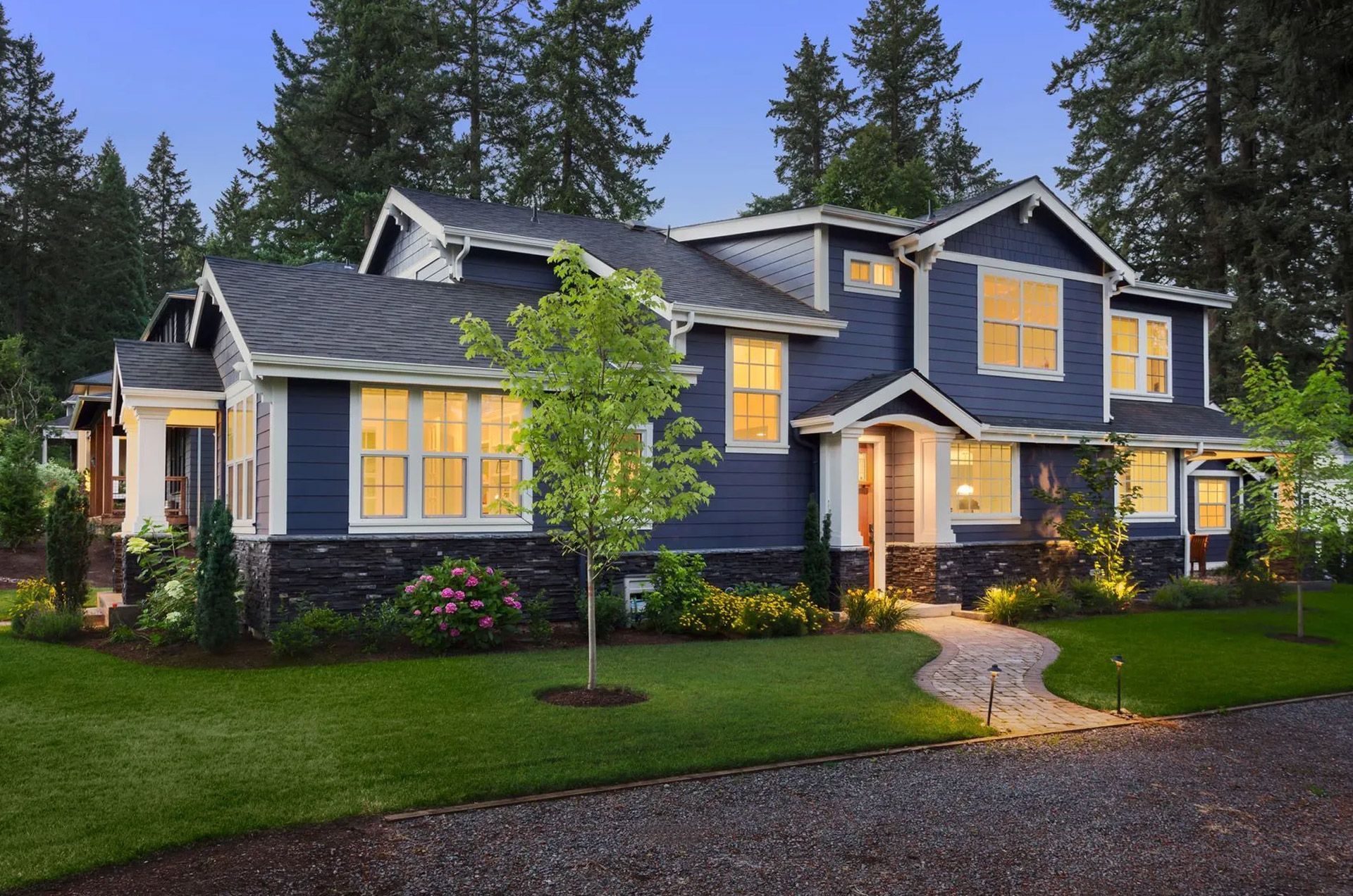 A large blue and white house with lots of windows is lit up at night.