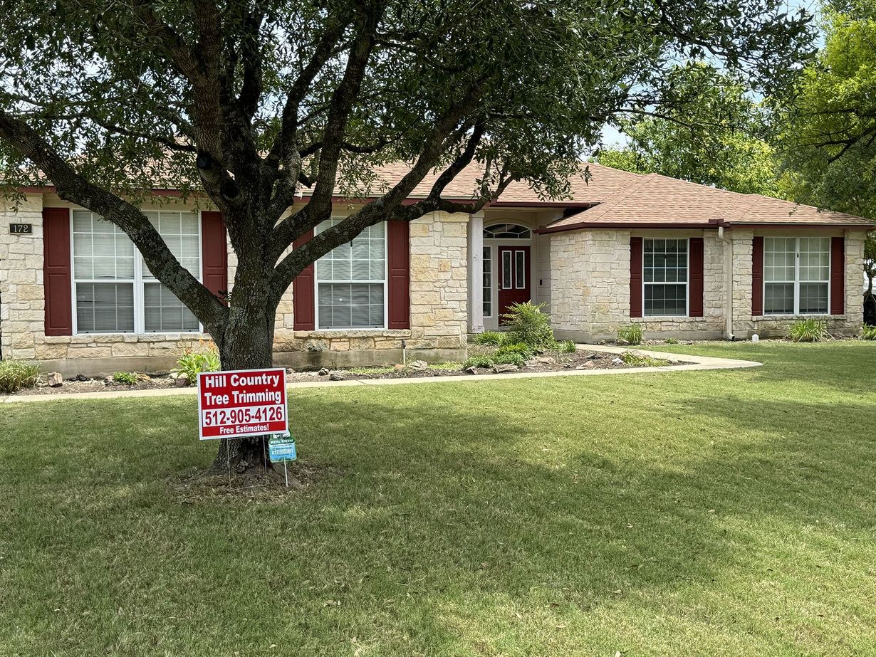 Single-story house with stone facade, red shutters, and a "For Sale" sign in front yard.