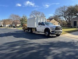 White garbage truck on a residential street under a blue sky.