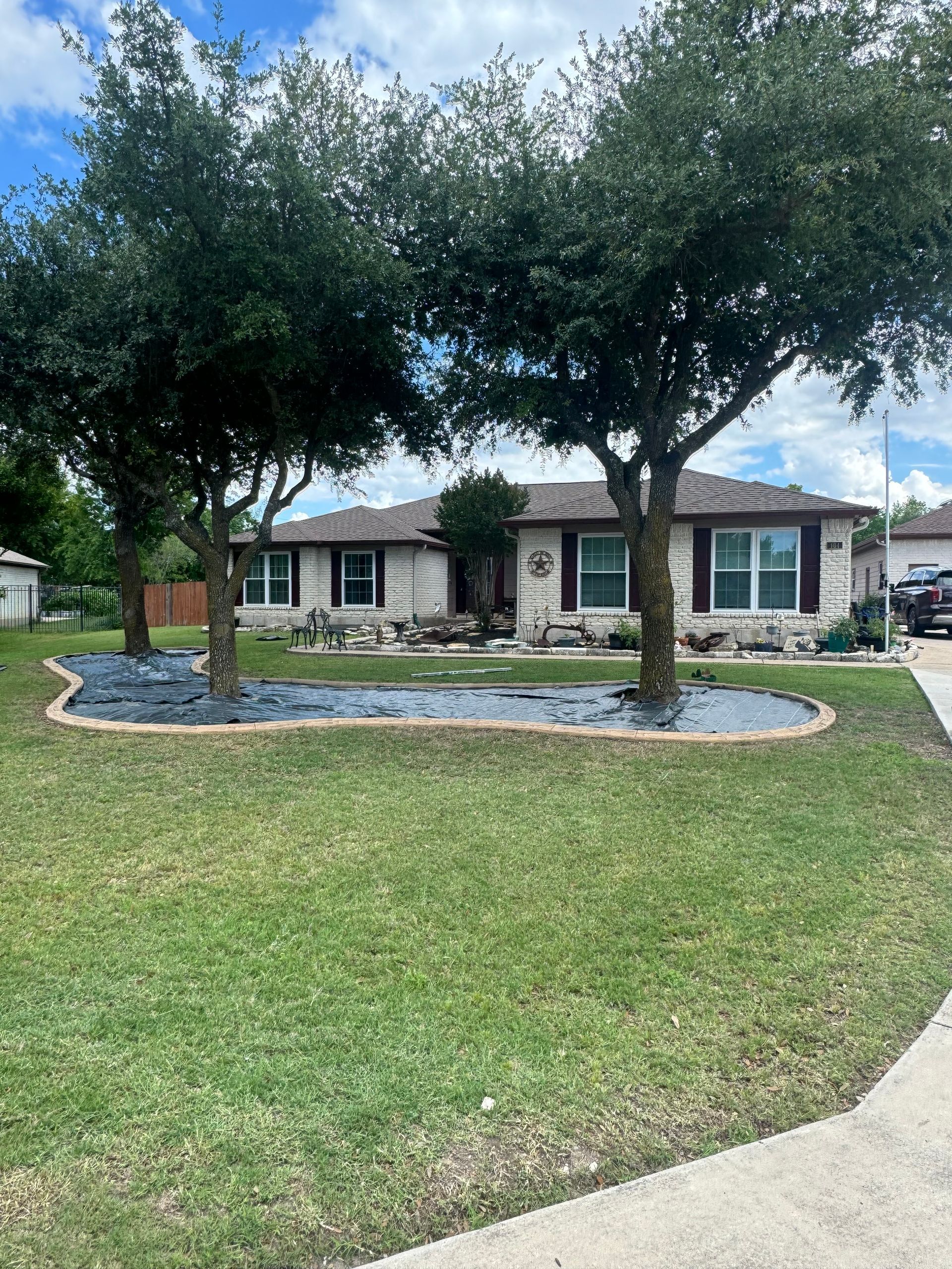 A single-story house with trees and a landscaped front yard.