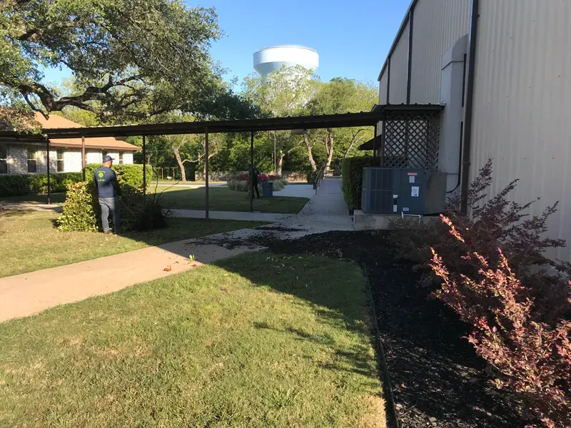 A covered walkway leads past a building and landscaping, with a water tower in the distance.