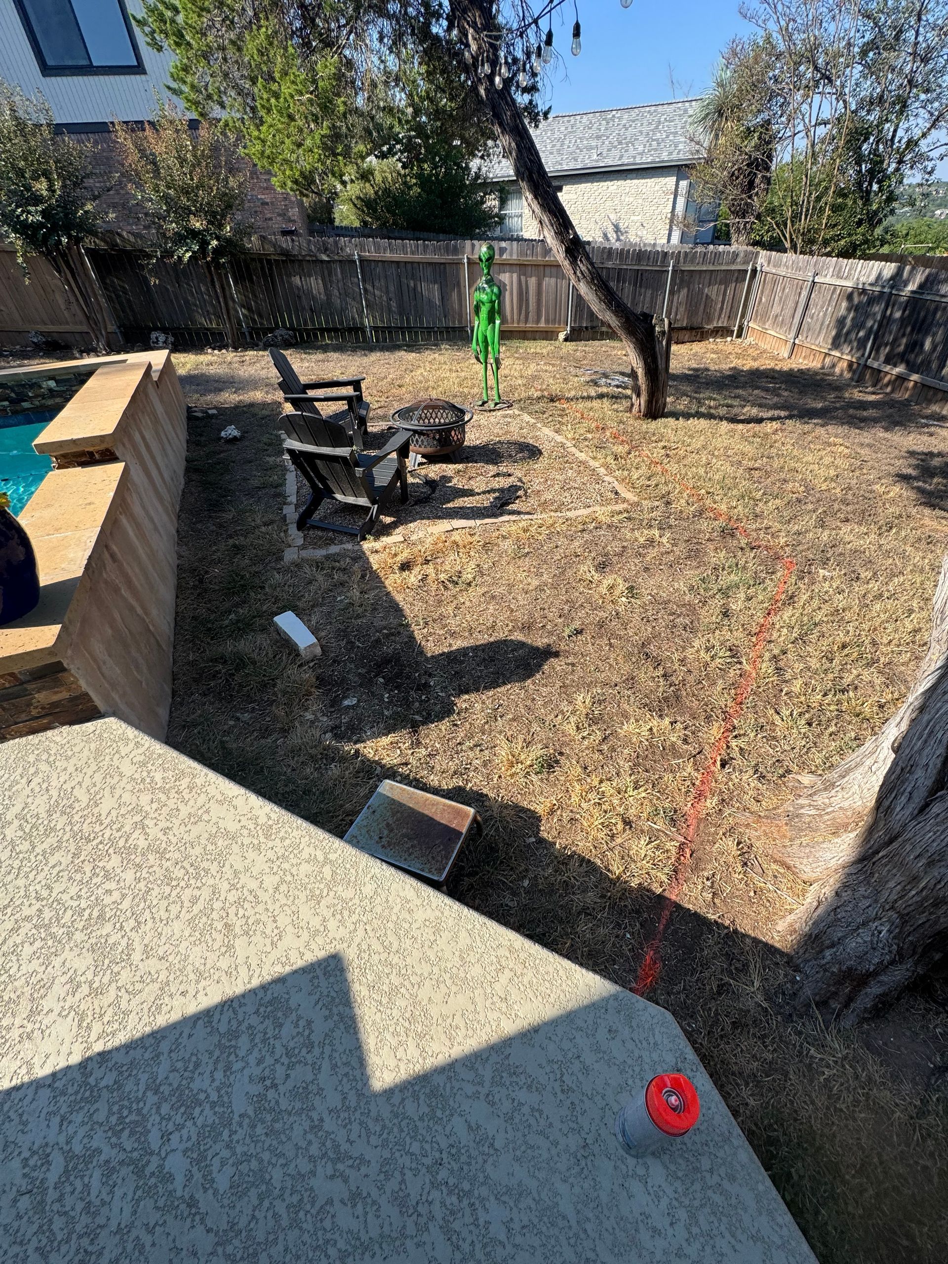 Backyard with pool, fire pit, and brown yard. Sunlit with low-growing vegetation and tree.