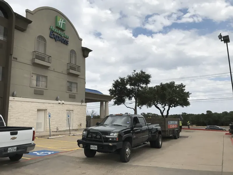 Black pickup truck in front of a Holiday Inn Express. Cloudy sky above.