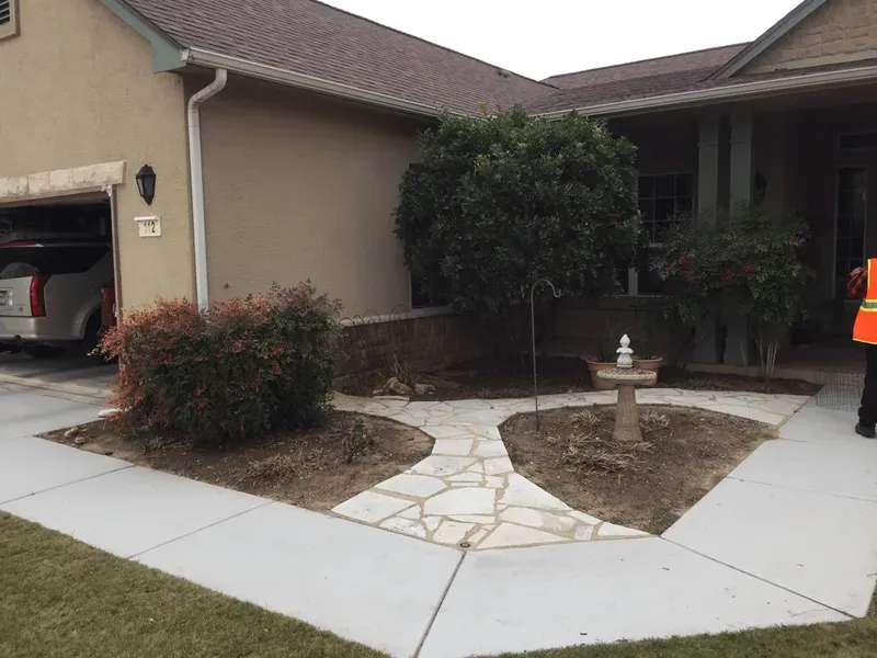 Exterior of house with stone walkway, landscaping, and a bird bath. A car is visible in the garage.