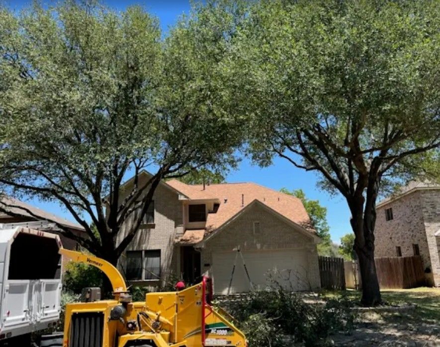 Tree trimming crew with chipper near a house.