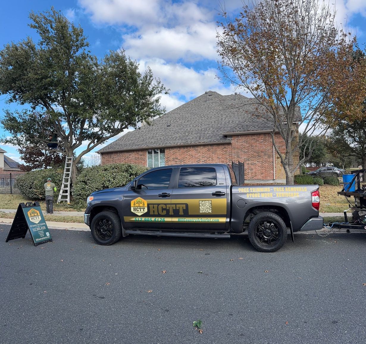 Truck with company logo parked in front of a house. A-frame sign and ladder visible.