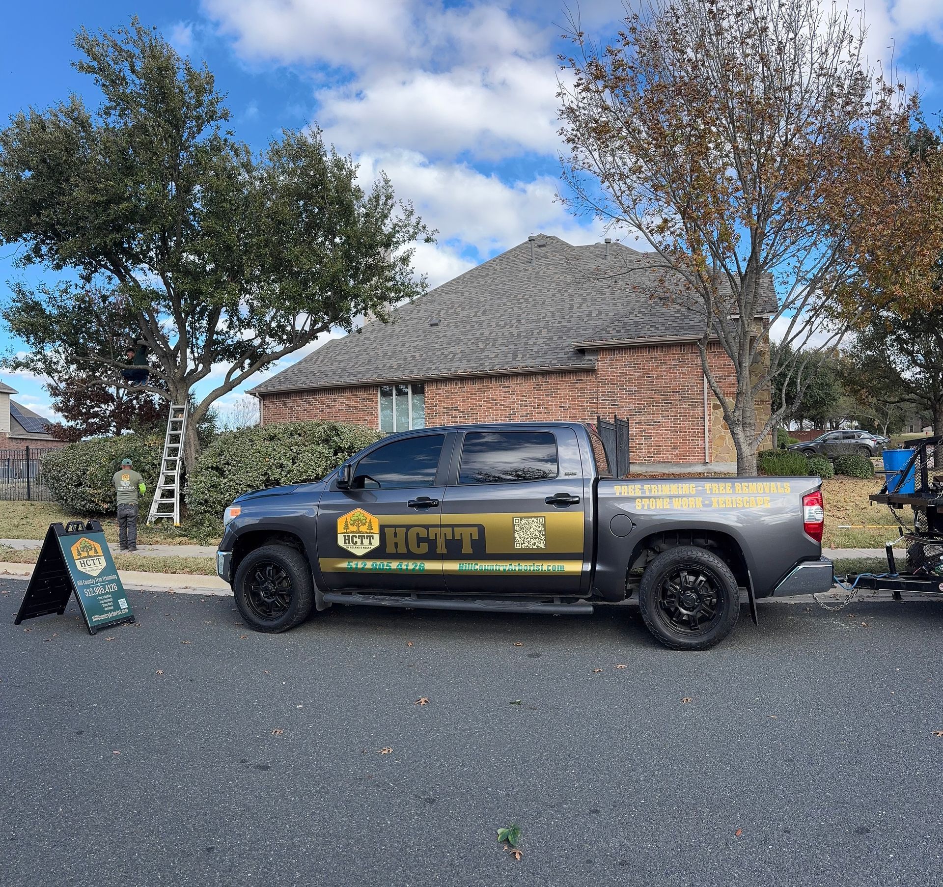 Truck with company logo parked in front of a house. A-frame sign and ladder visible.