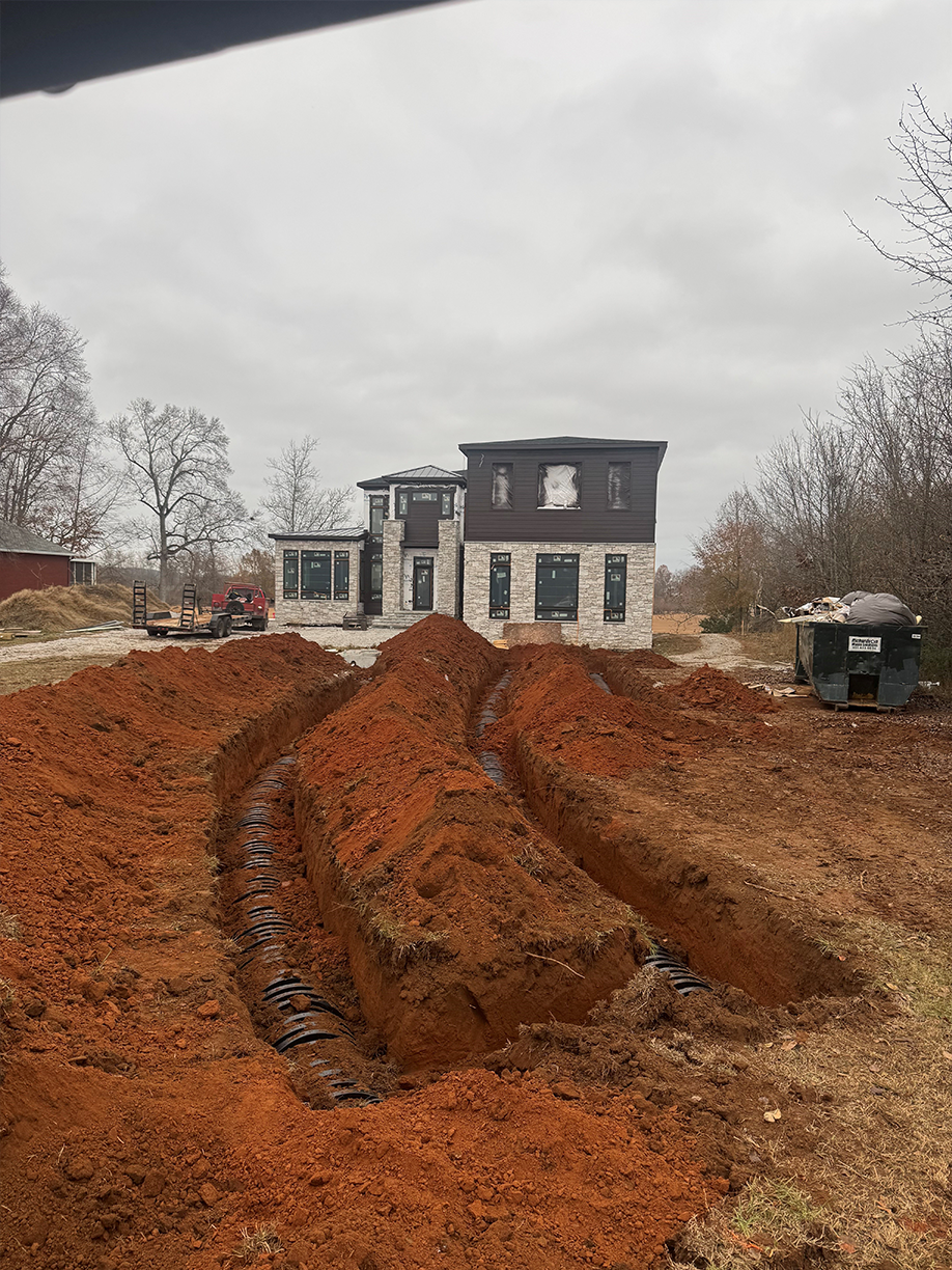 A large pile of dirt is sitting in front of a house under construction.