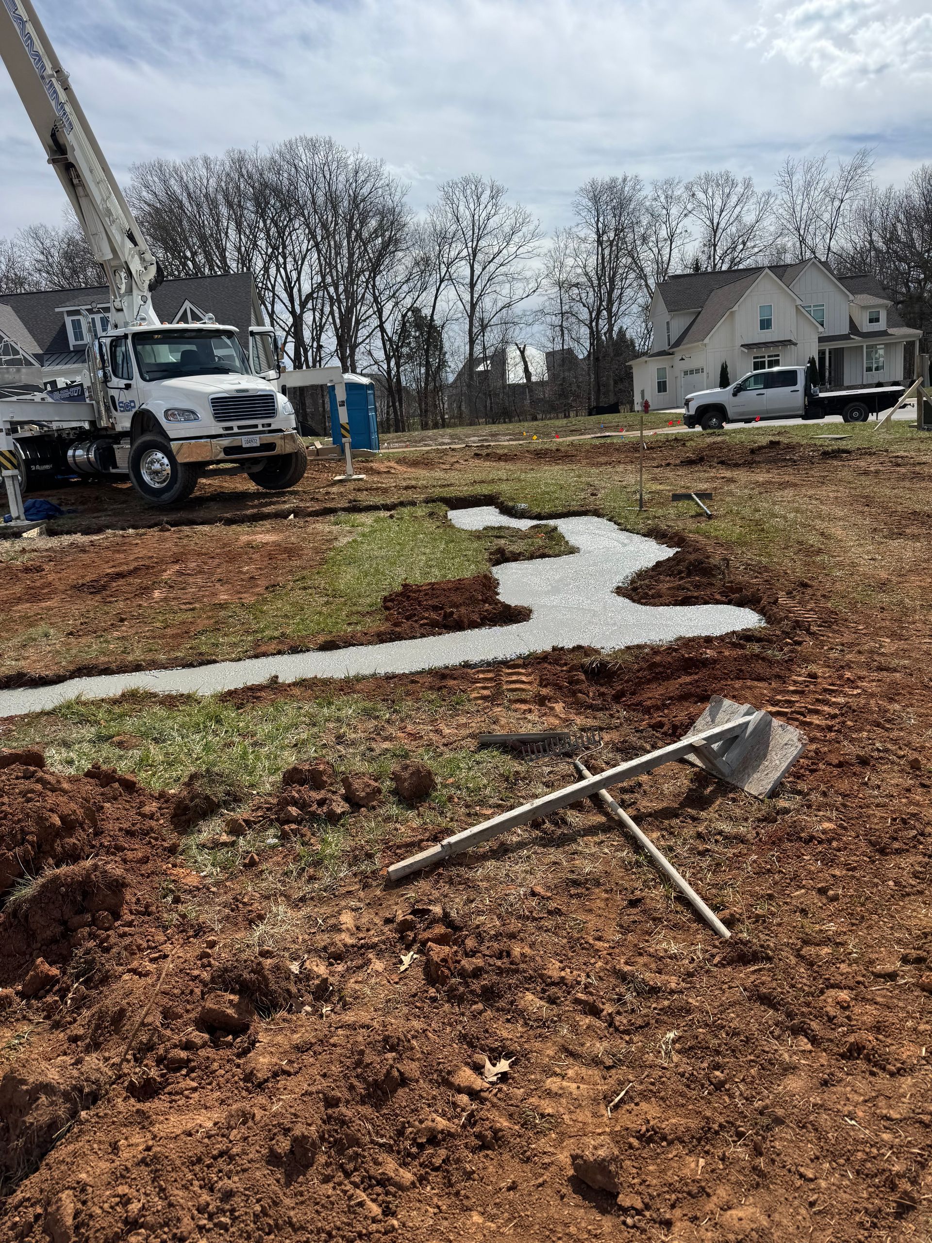 A construction site with a crane and a shovel in the dirt.