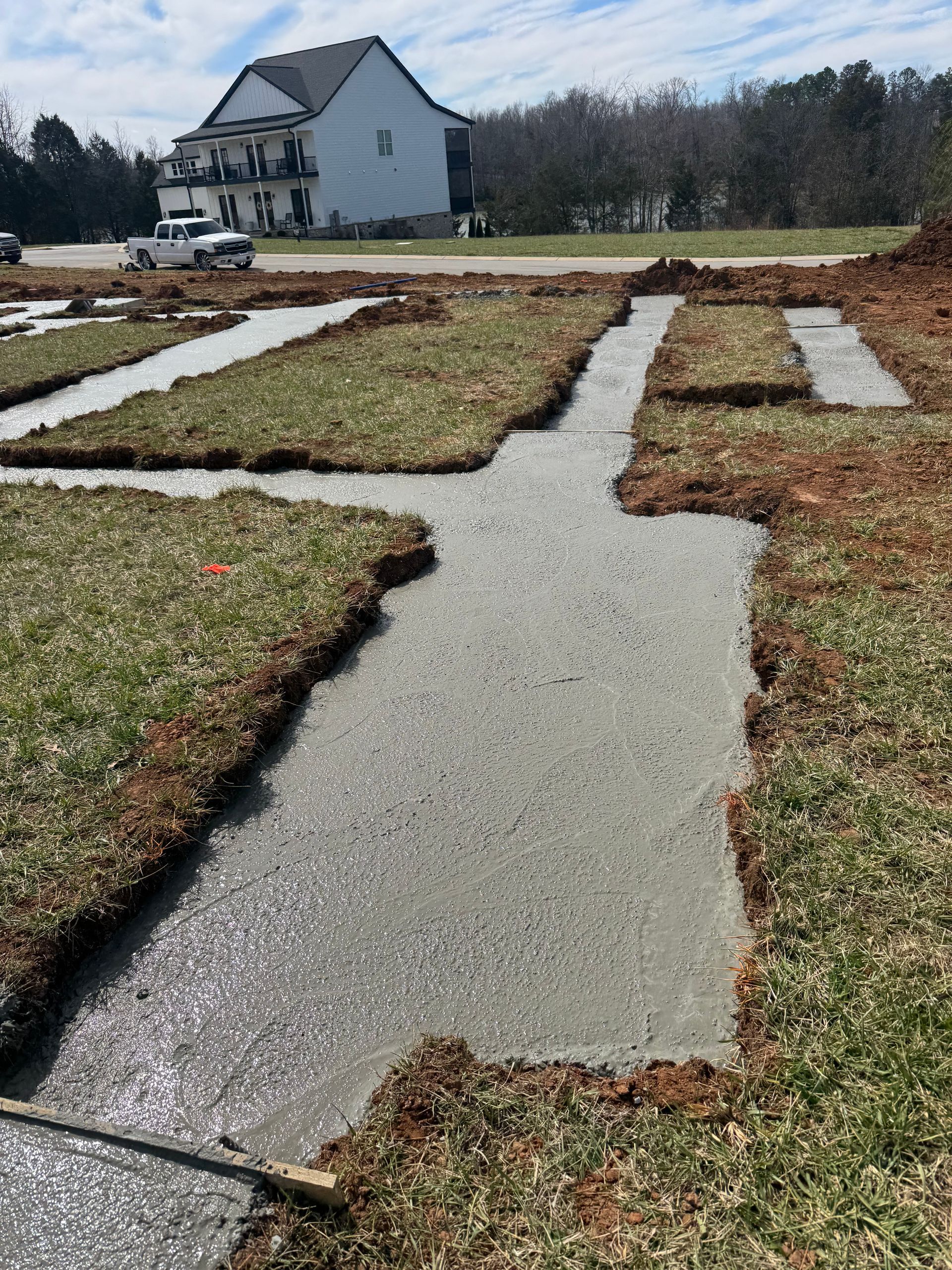 A concrete walkway is being built in a yard with a house in the background.