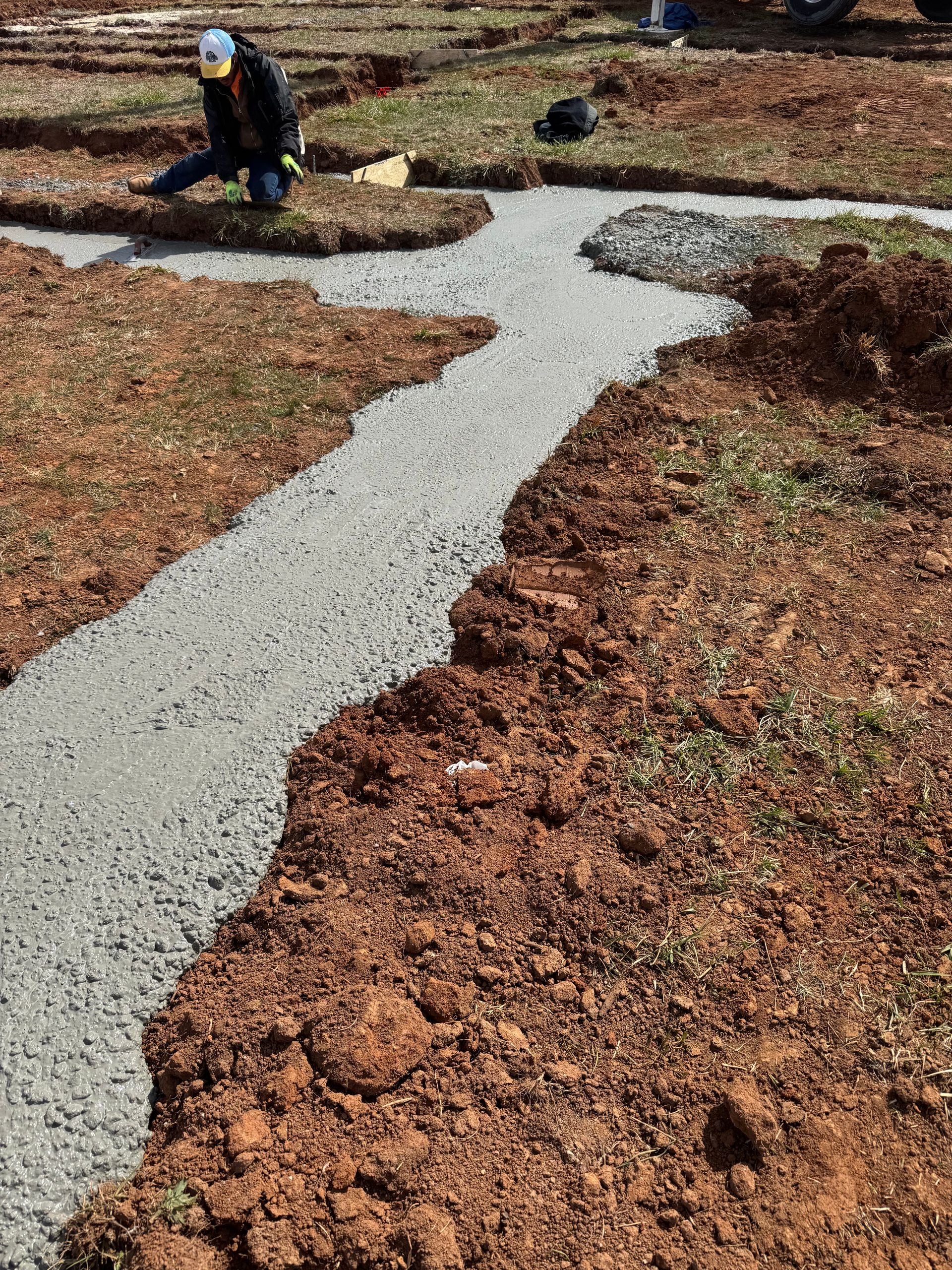 A man is laying gravel on top of a dirt field.