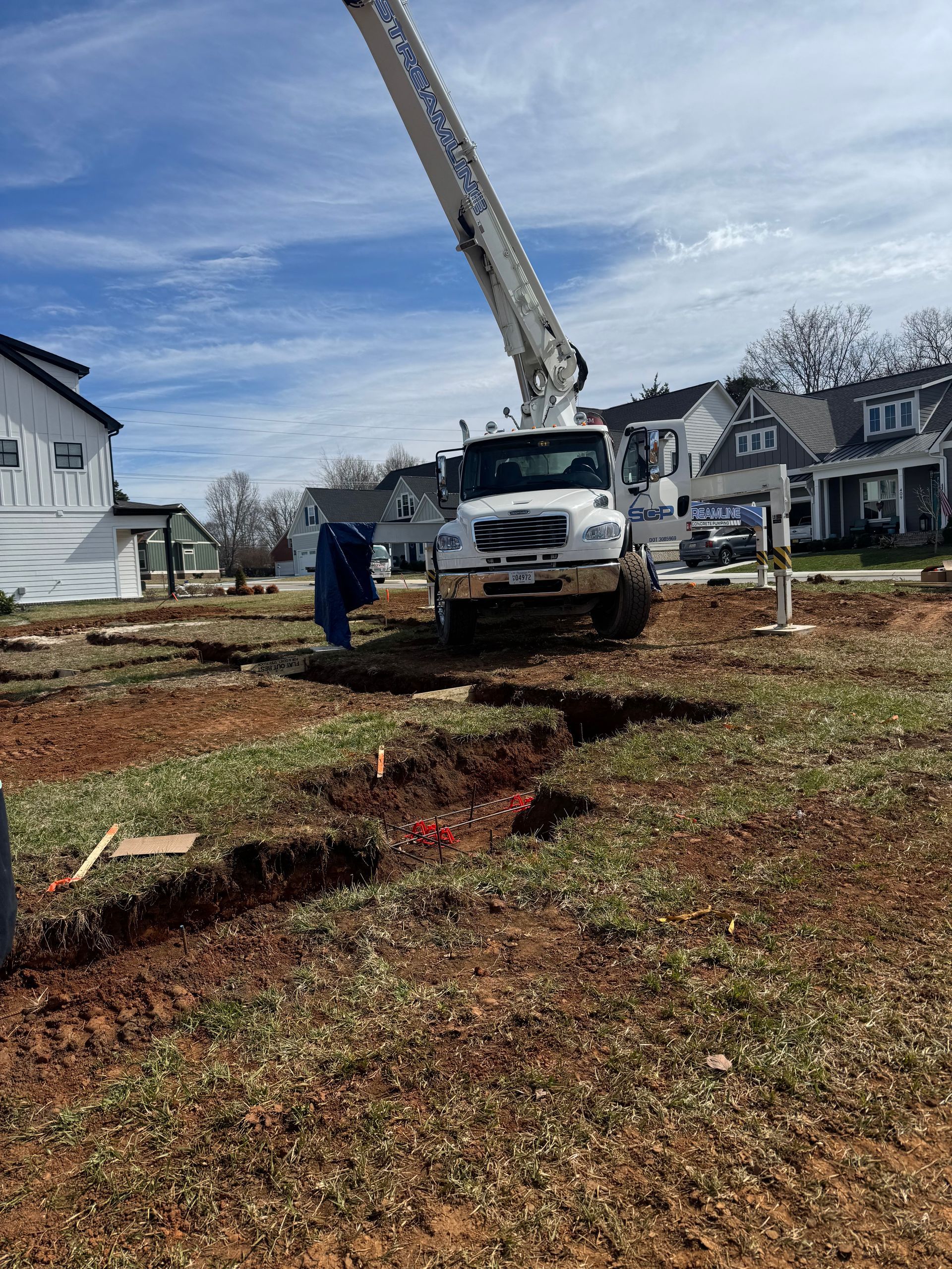 A crane is sitting on top of a dirt field next to a house.