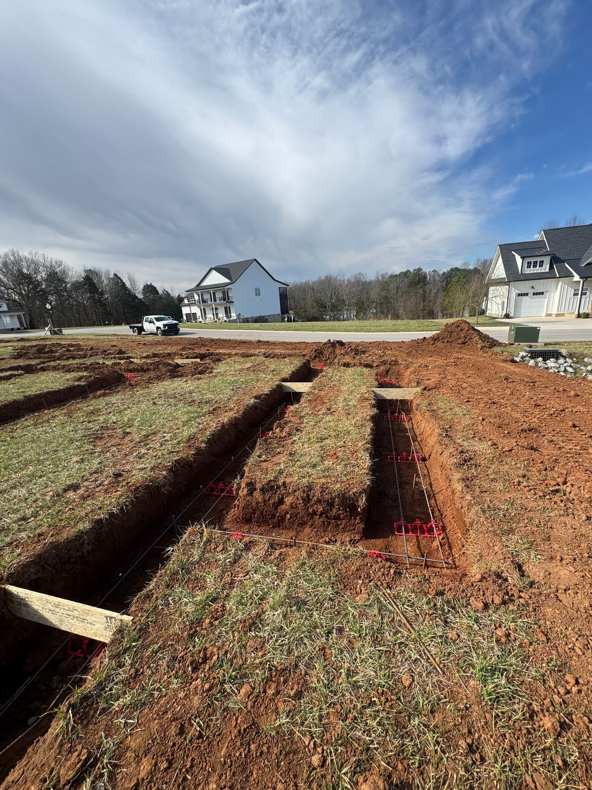 A construction site with a lot of dirt and a house in the background.