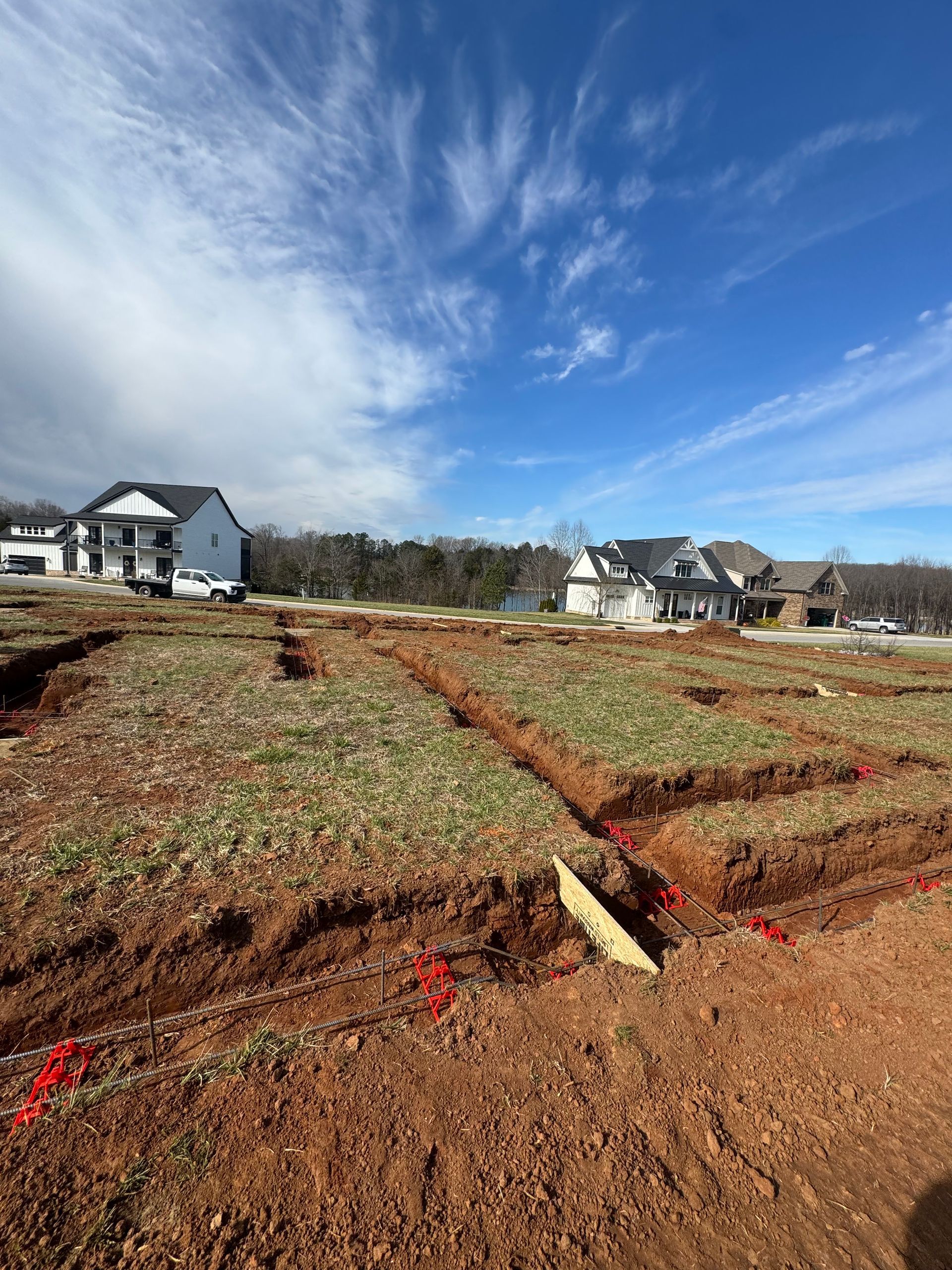 A large dirt field with a house in the background.