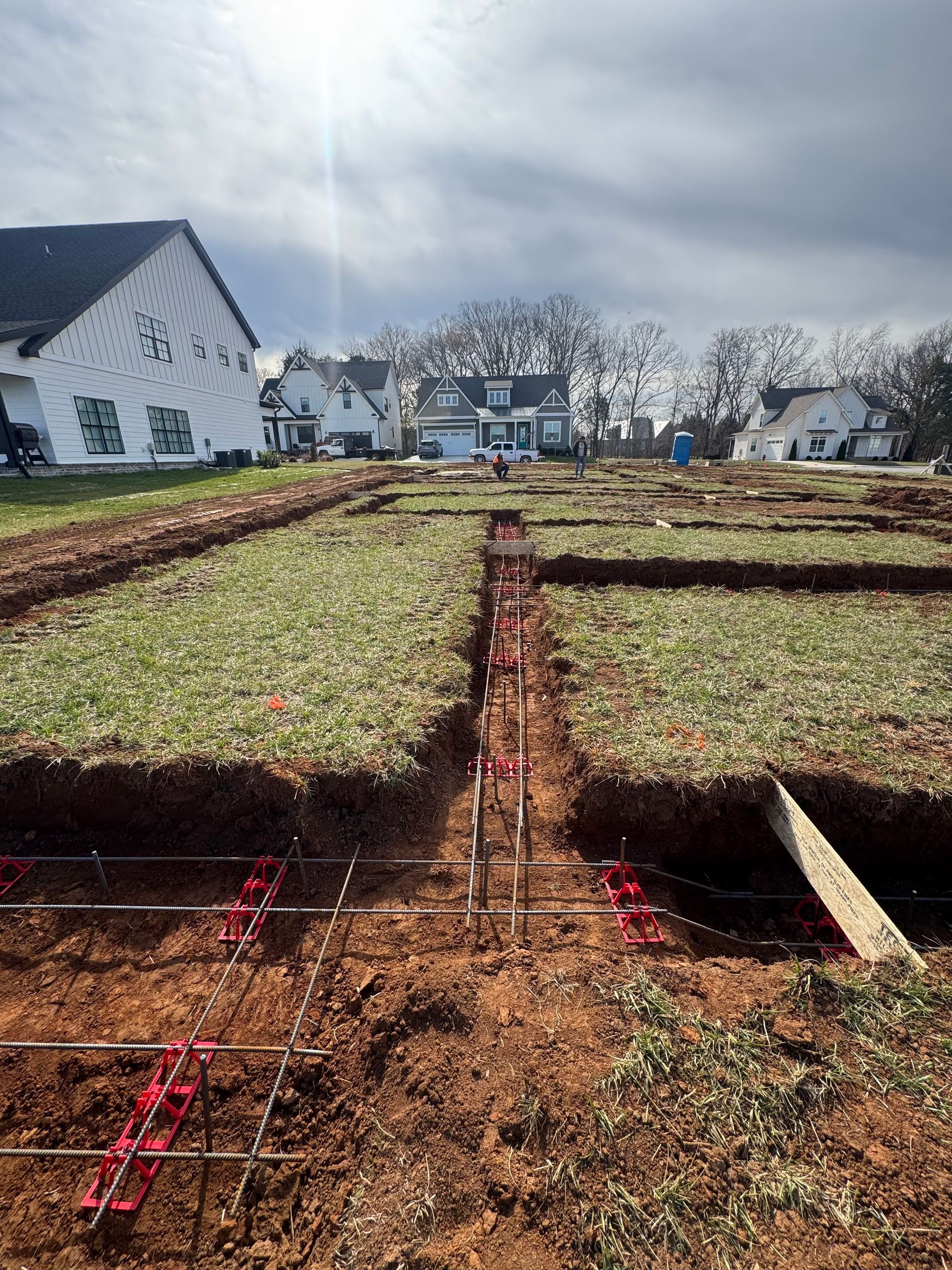 A large dirt field with a white house in the background.