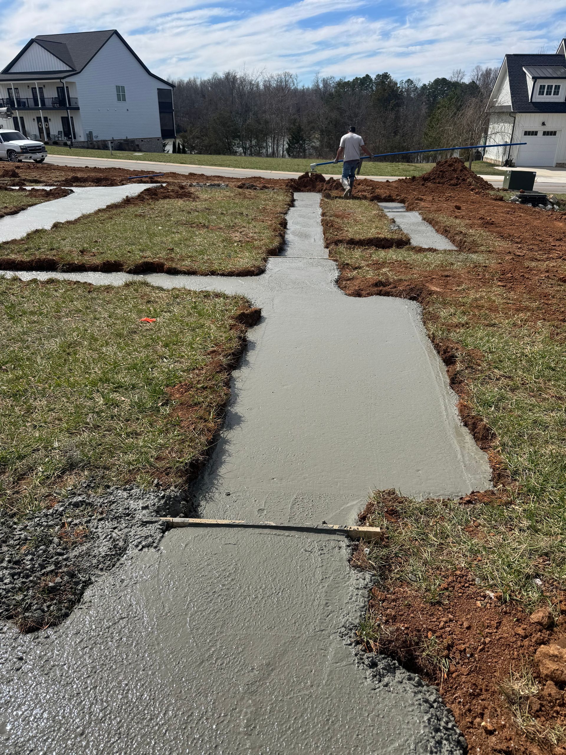 A man is walking down a concrete walkway in a yard.